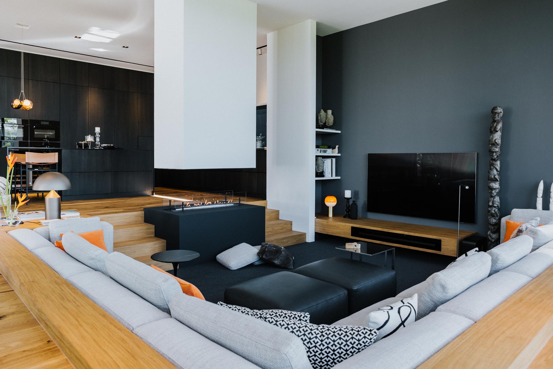 Offener Wohnbereich mit großzügiger Sofalandschaft, Kamininsel, TV-Board und integrierter Küche