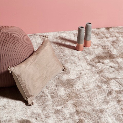 Roséfarbener Teppich vor rosafarbener Wand mit Dekokissen und Vasen