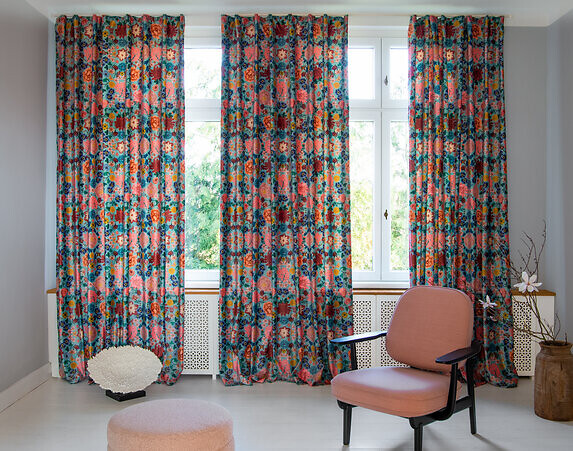 Drei bunt gemusterte Vorhänge vor einem Fenster mit Blick ins Grüne