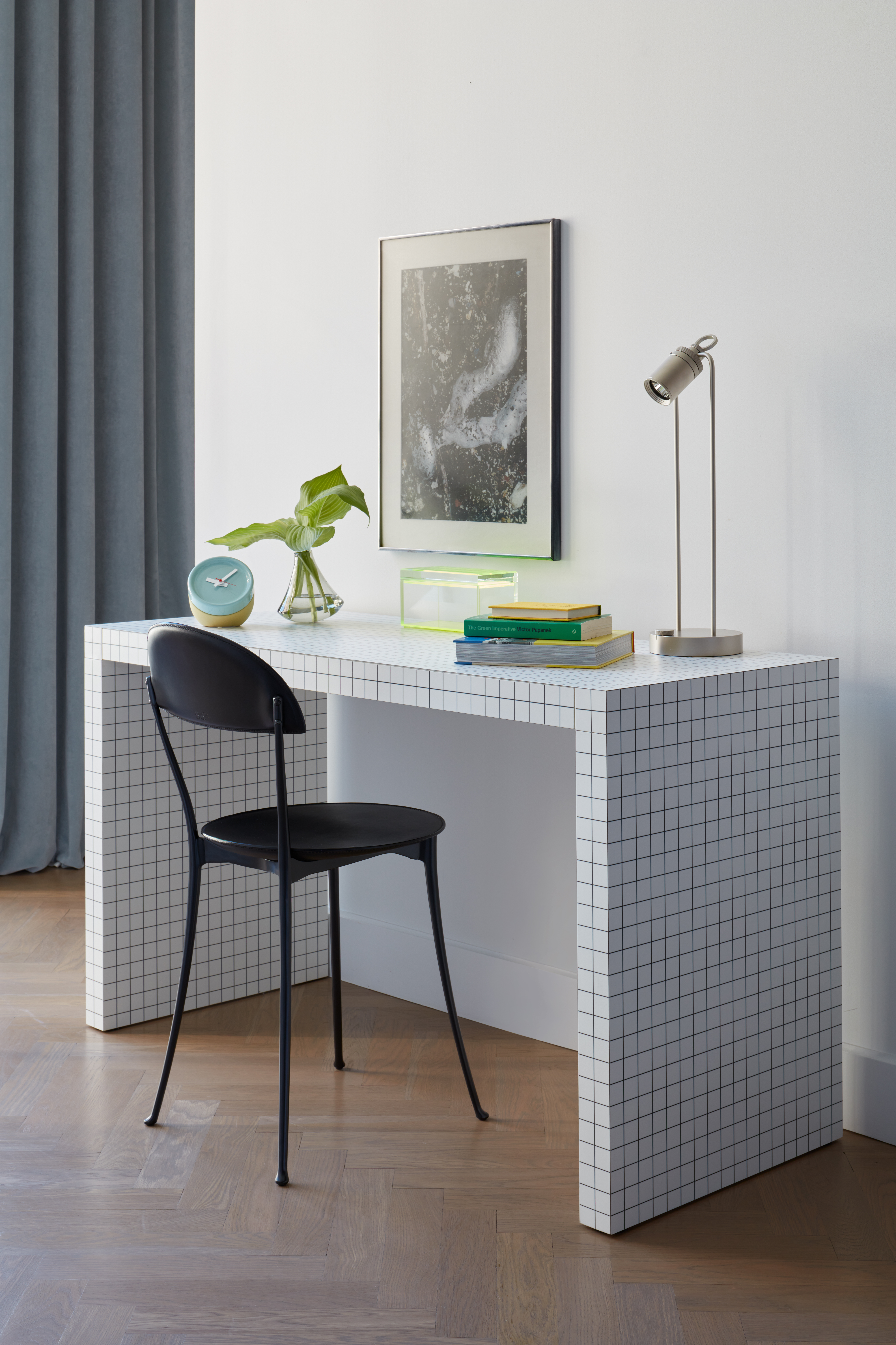 Weißer Schreibtisch mit Kachelstruktur und schwarzem Stuhl in einer wohnlichen Umgebung mit Holzfußboden