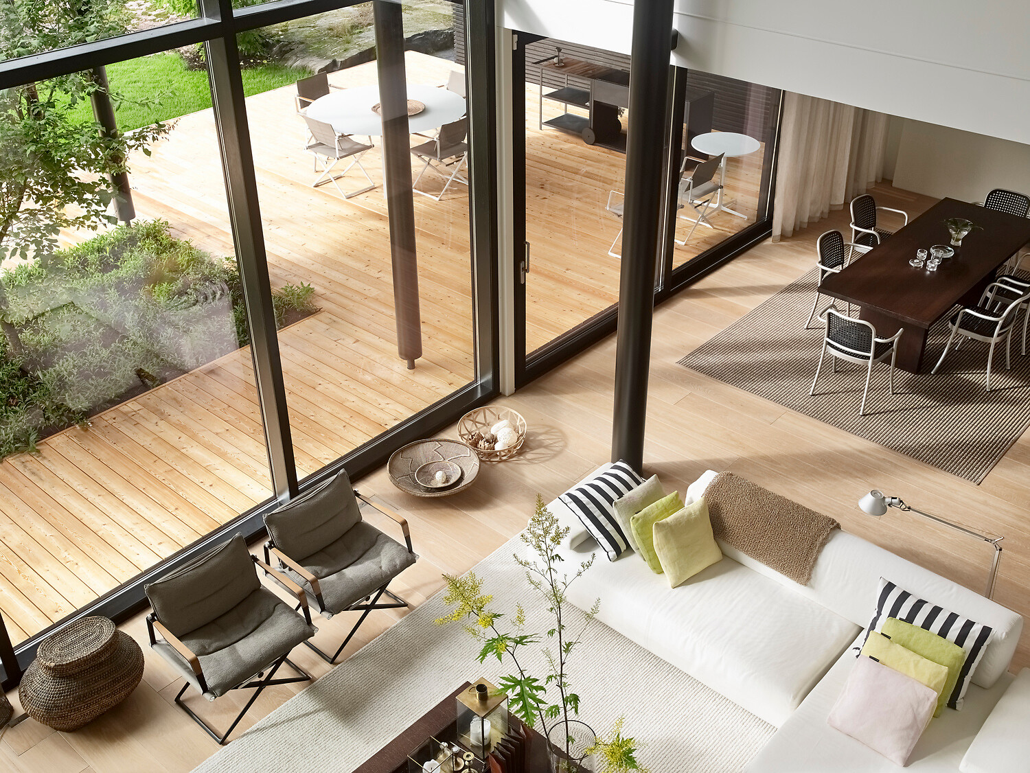 Offener Wohnraum mit Sofalandschaft, Teppichen und Ausblick auf Holzterrasse