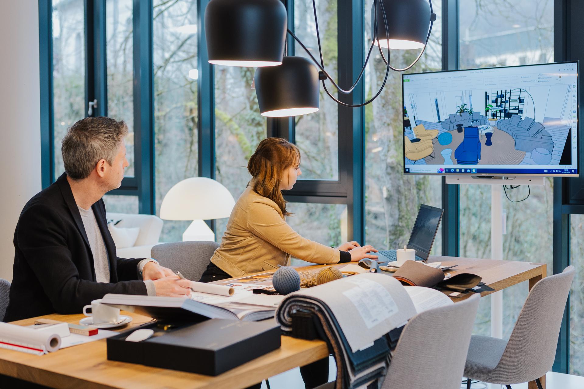 Zwei Personen bei Seipp Wohnen im Planungsprozess mit Stoffmustern und Visualisierung am Bildschirm.