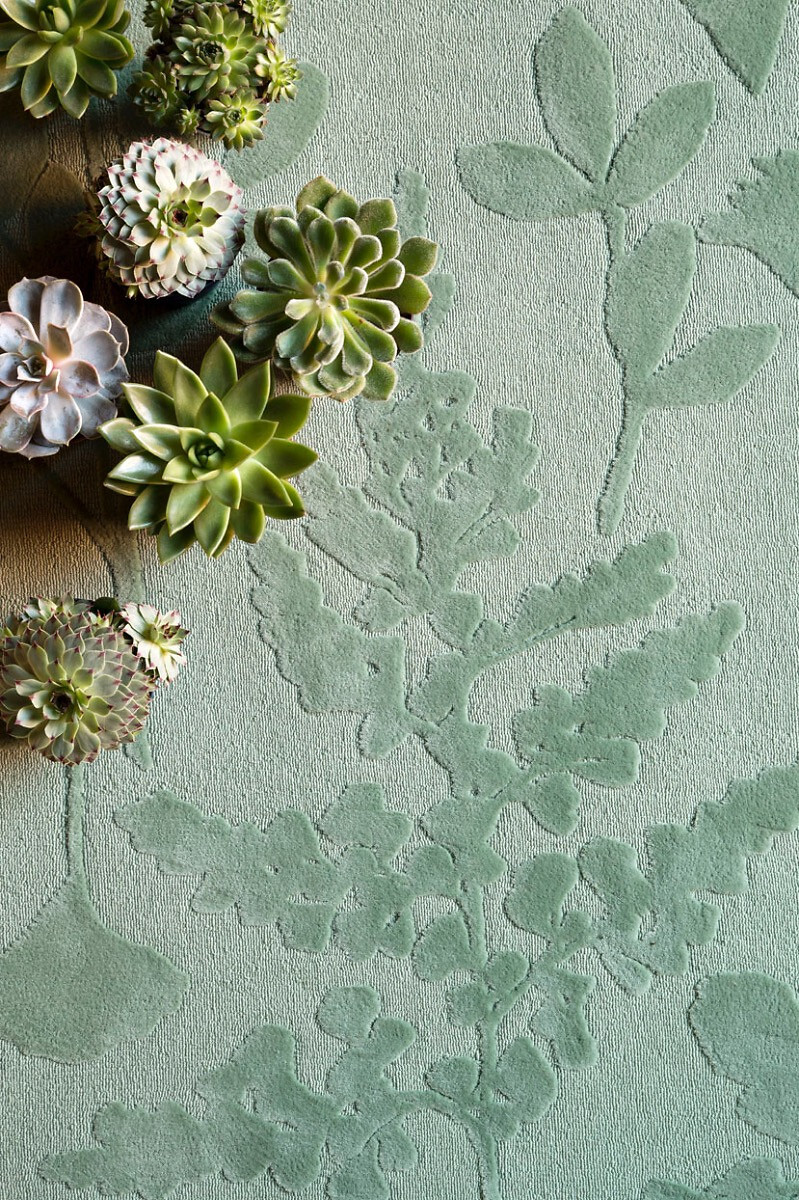 Hellgrüner Teppich mit eingeprägtem Blattmuster und Sukkulenten  
