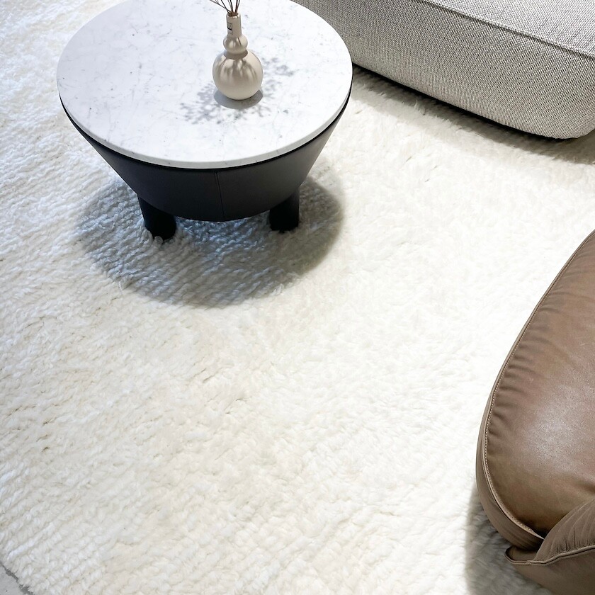 Hochflorteppich in Wollweiß mit Couchtisch aus Marmor und Vase