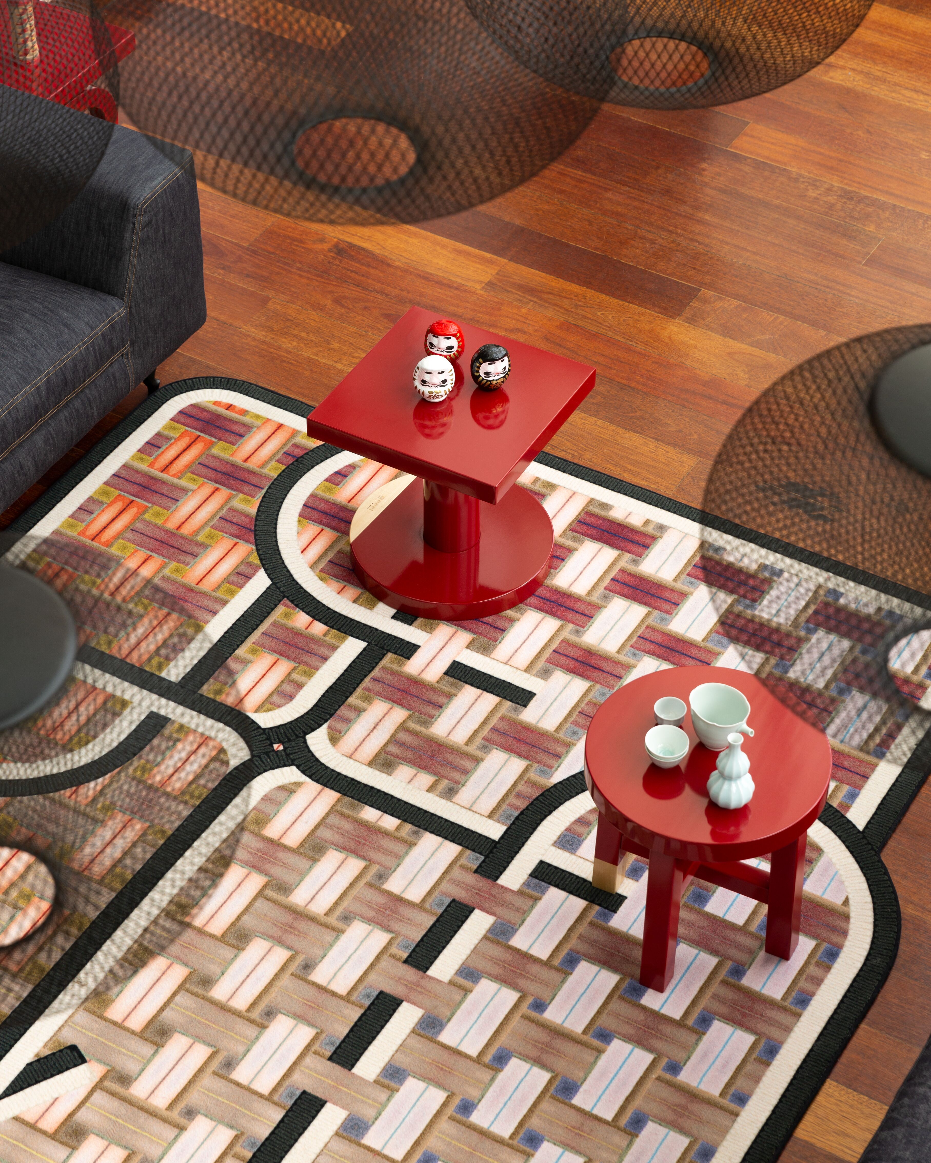 Geometrisch gemusterter Teppich mit roten Beistelltischen auf Holzfußboden  