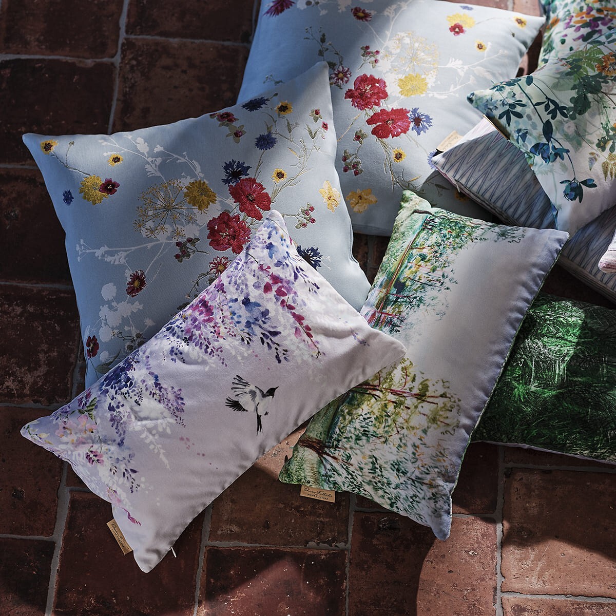 Zierkissen mit bunten floralen Mustern auf Steinboden arrangiert