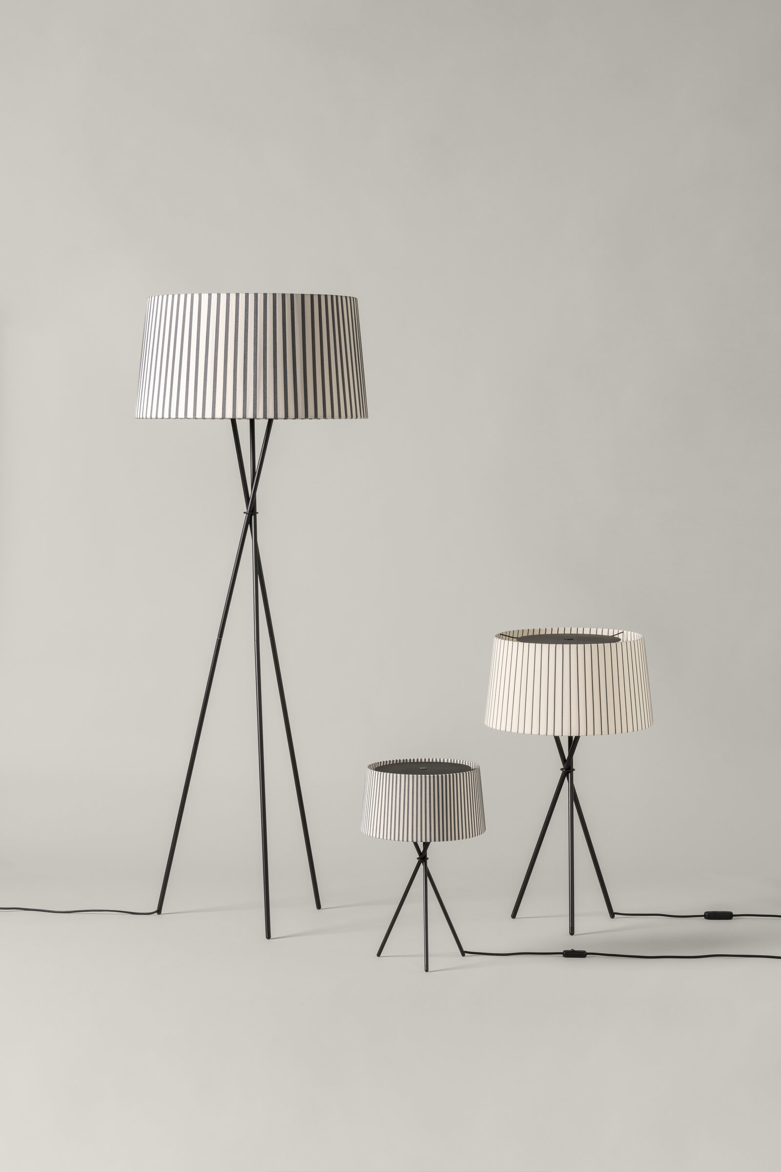 Drei Santa & Cole Tripode-Leuchten in unterschiedlichen Größen vor grauem Hintergrund