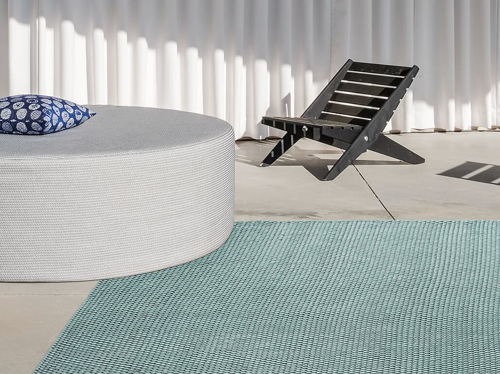 Flachgewebter Outdoorteppich in Türkis auf Terrasse mit Loungemöbeln und Lamellen