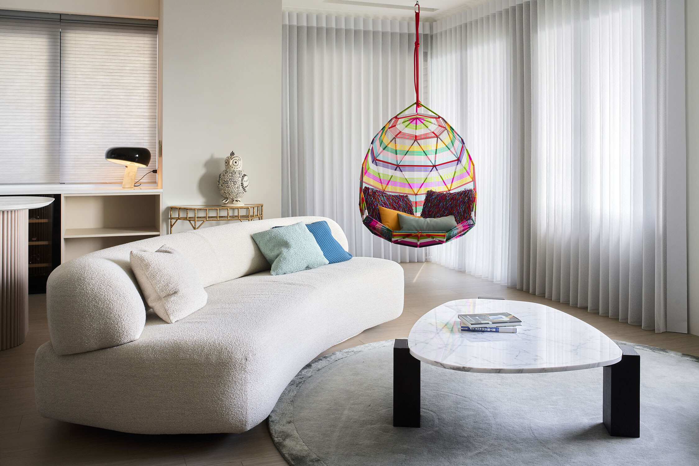 Helles Wohnzimmer mit Sofa, Marmor-Couchtisch und buntem Hängesessel