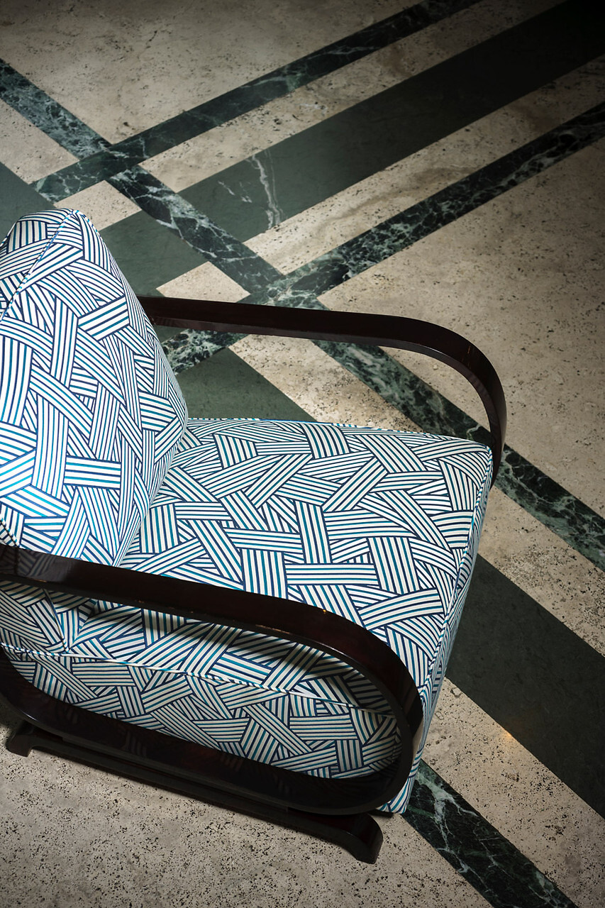 Sessel mit schwarz-weiß gemustertem Dedar-Stoff auf marmoriertem Boden mit Streifendekor