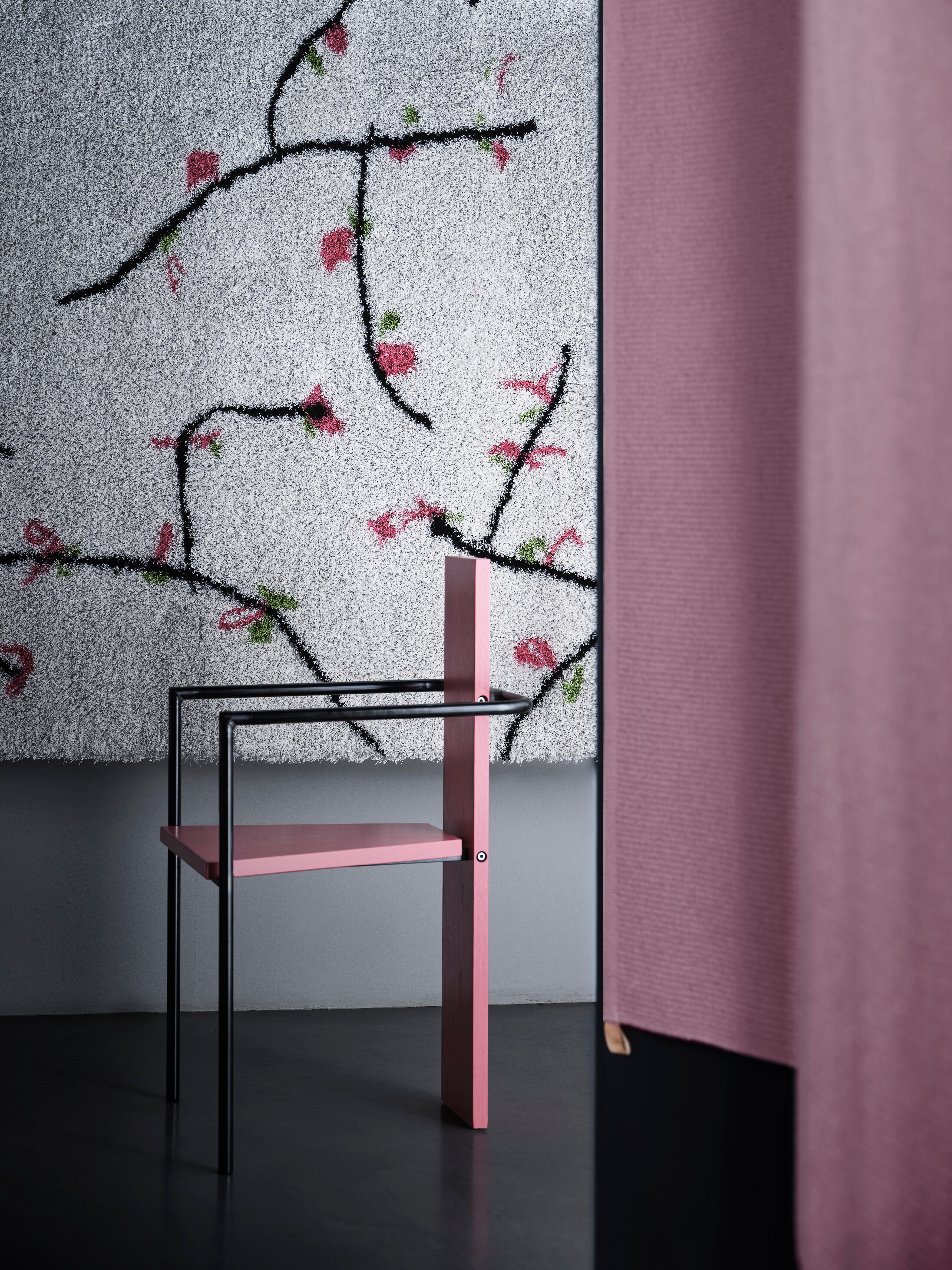 Teppich mit floraler Linienstruktur hinter skulpturalem Stuhl in Rosa und Schwarz  