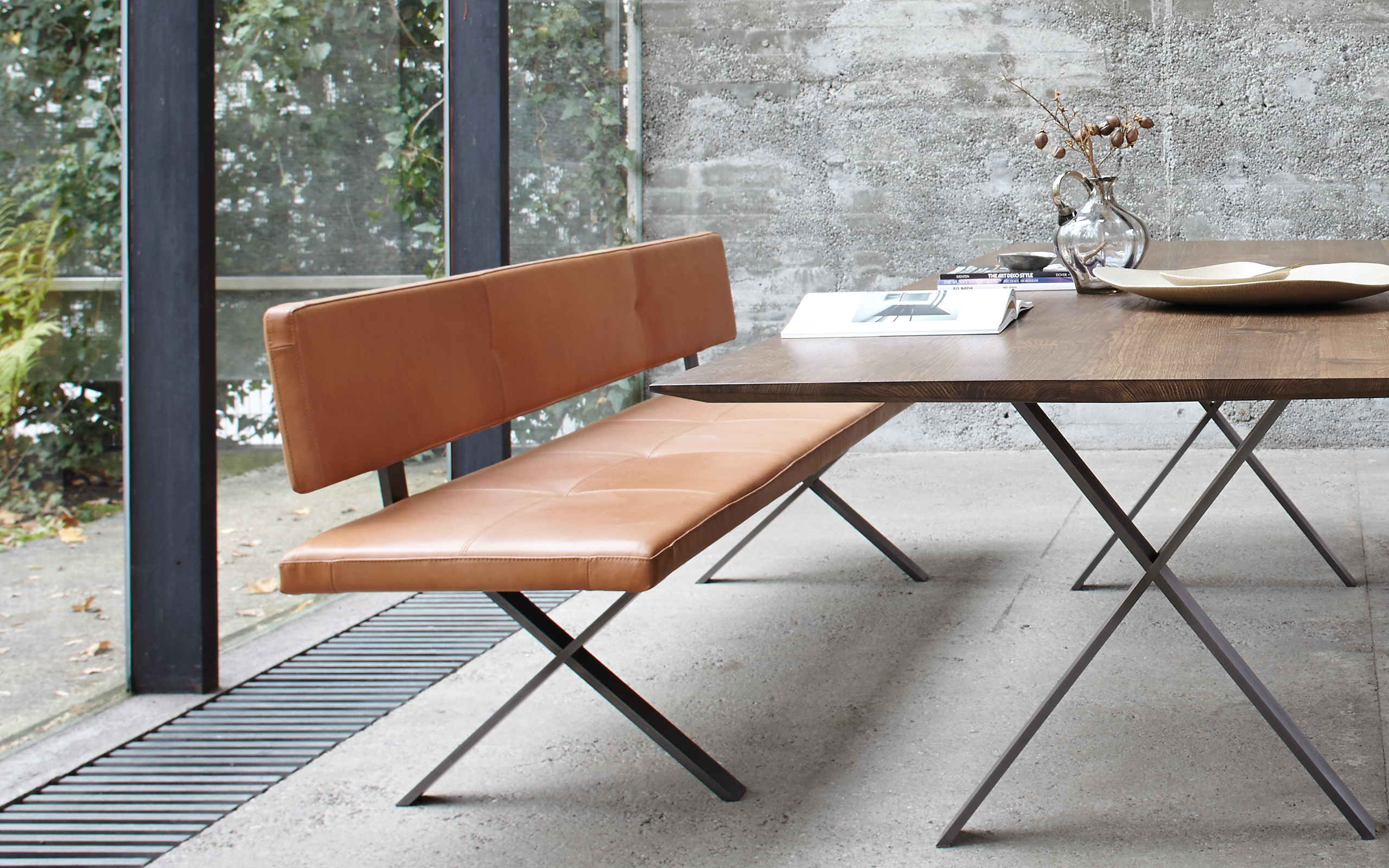 Schlichte Lederbank mit Rückenlehne an einem rechteckigen Tisch mit Metallgestell  