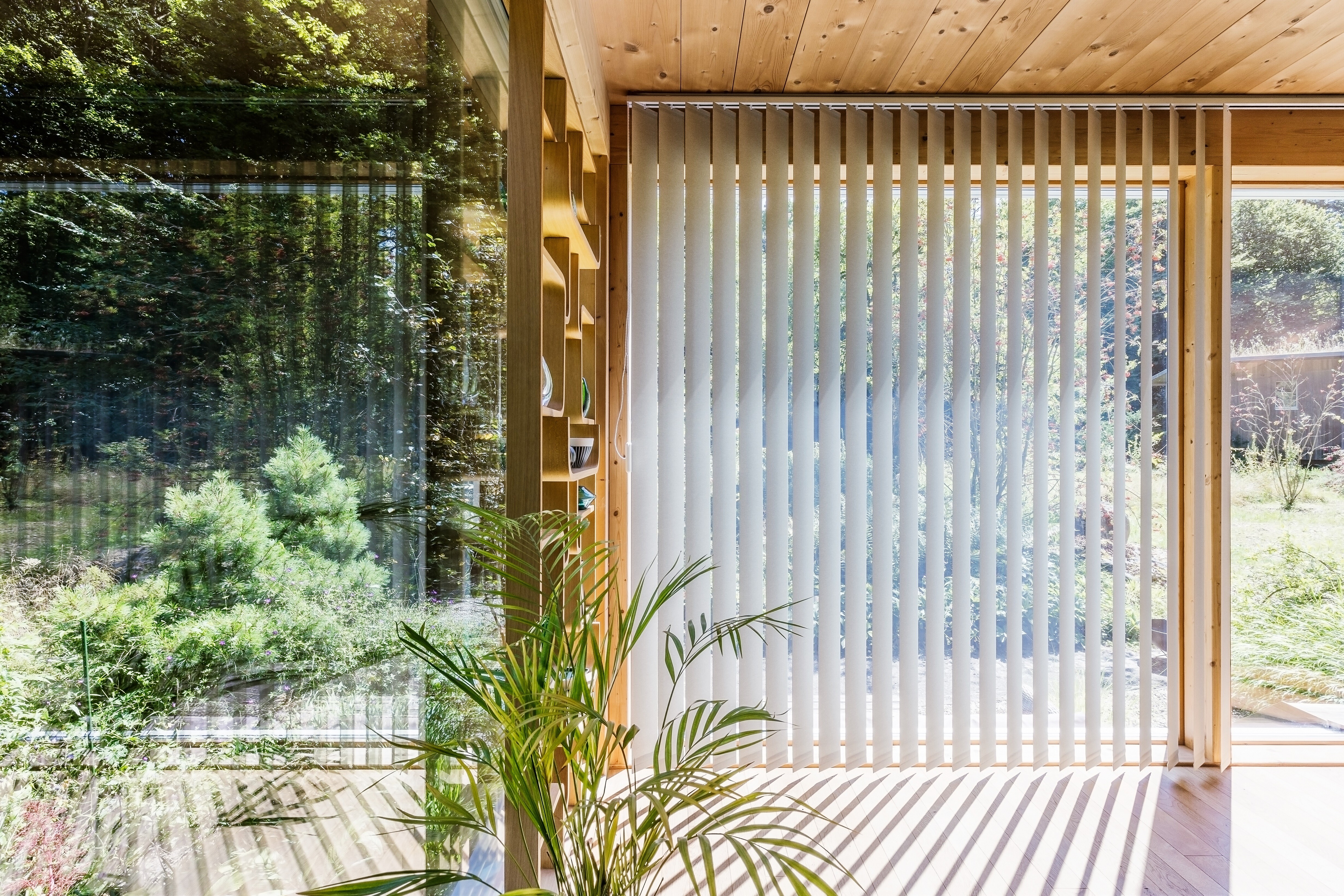 Vertikallamellen von Création Baumann vor bodentiefer Fensterfront im Sonnenlicht  