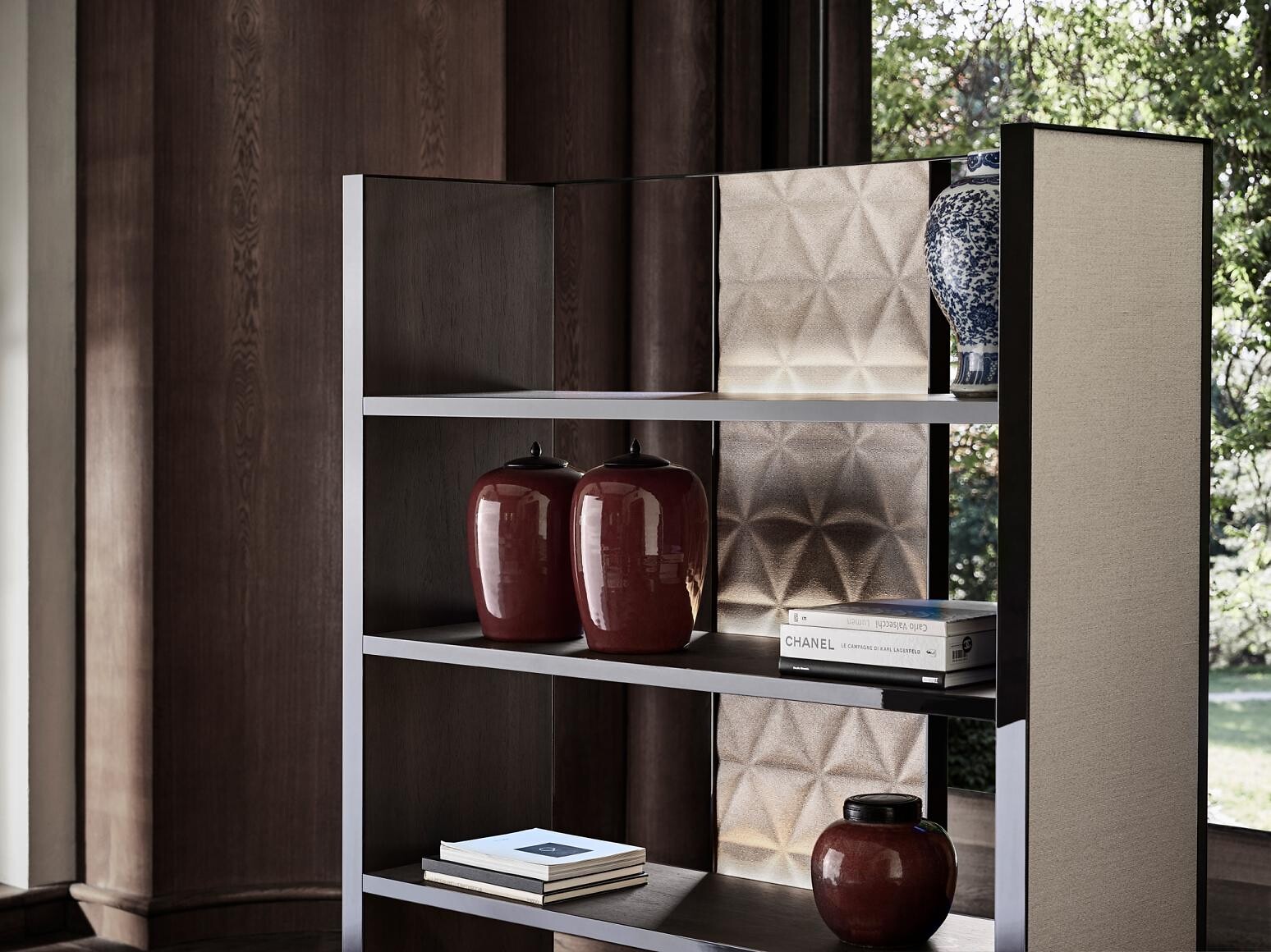 Offenes Regal mit Dekoobjekten vor Fenster und dunkler Holzvertäfelung