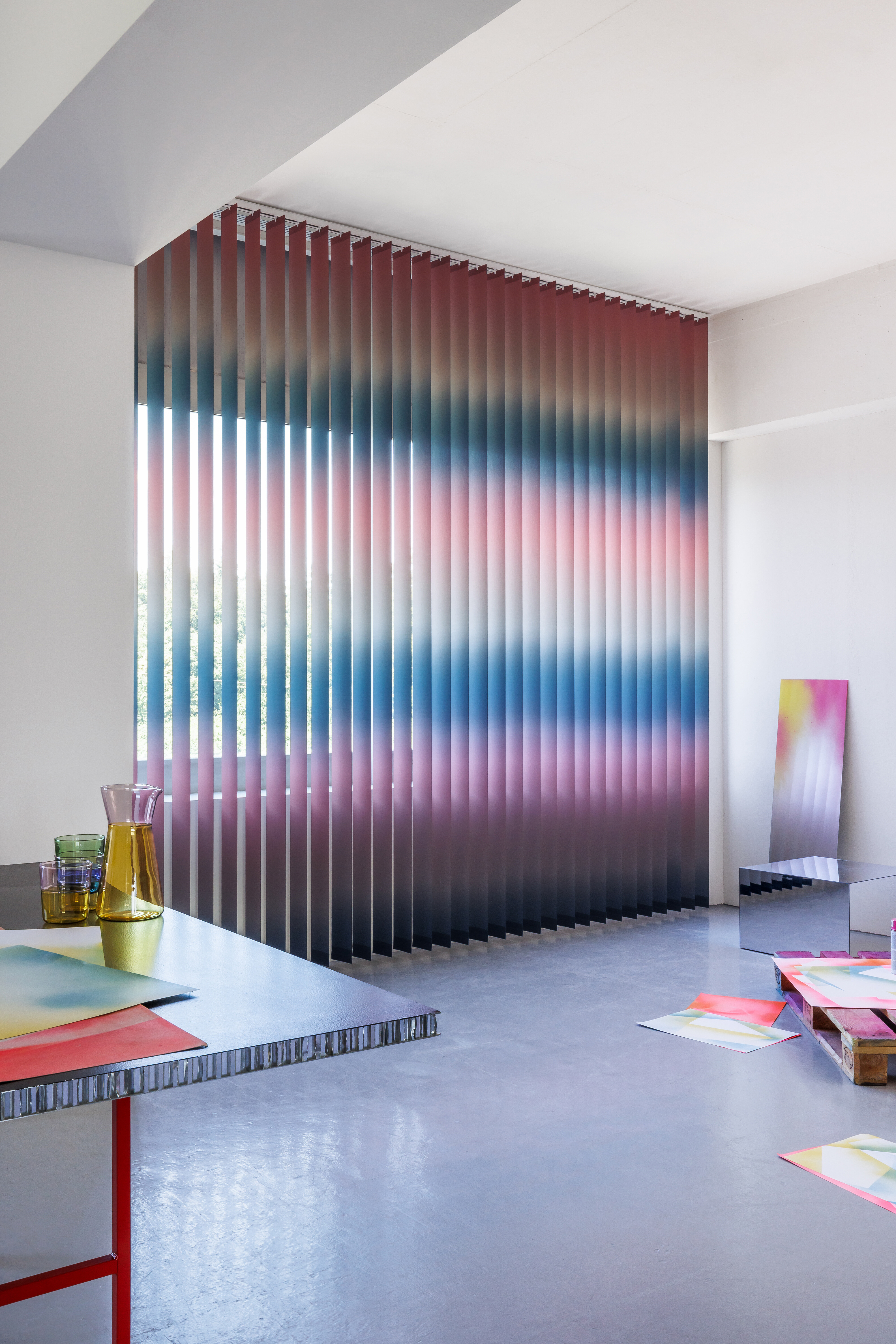 Vertikale Lamellen in Farbverlauf als Sichtschutz in einem modern gestalteten Raum.