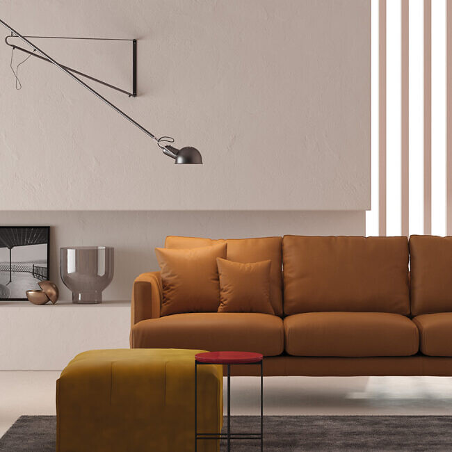 Cognacfarbenes Sofa mit ockergelbem Pouf, Beistelltisch und schwenkbarer Wandleuchte  