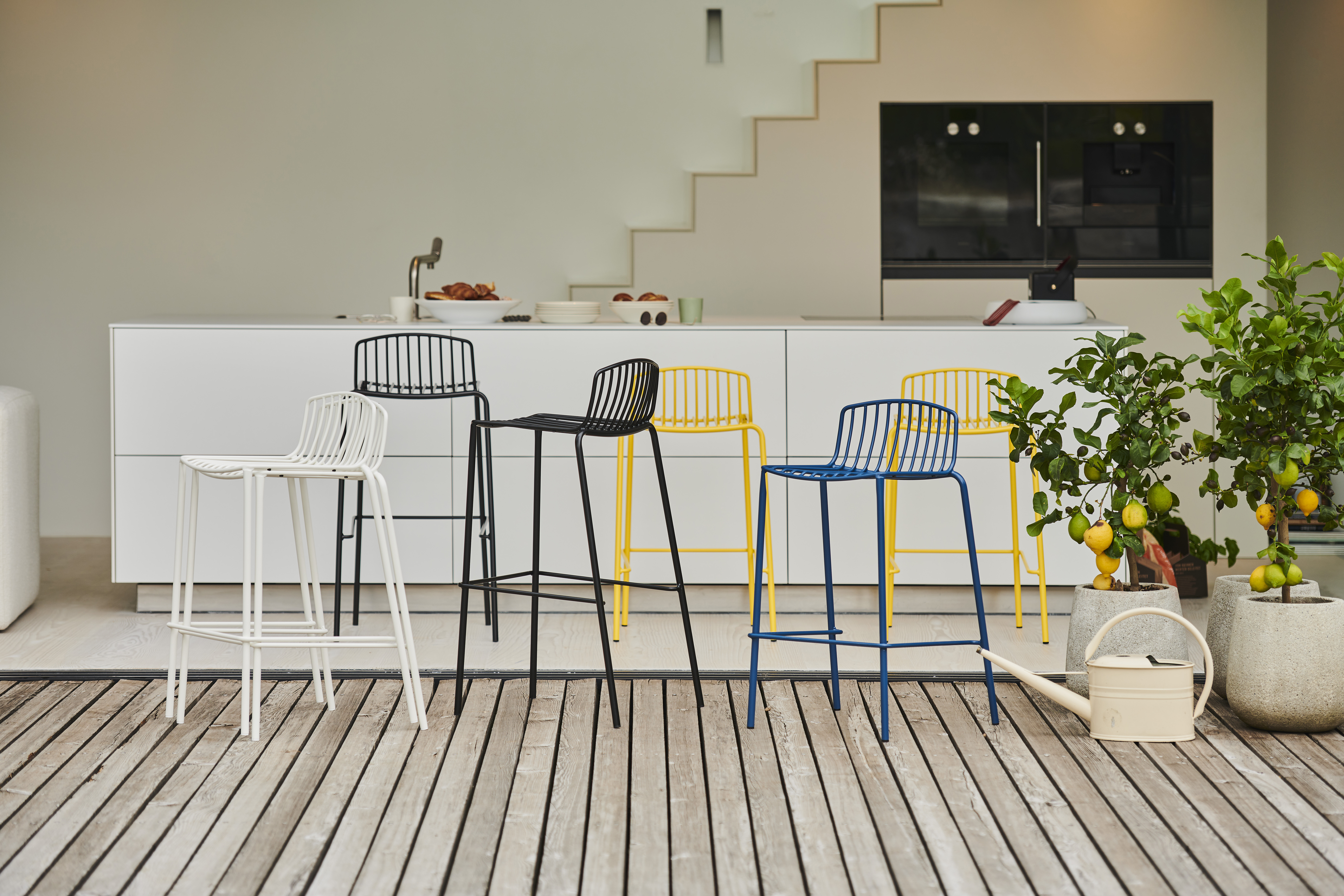 Sechs Jan Kurtz Barhocker in unterschiedlichen Farben vor weißer Kücheninsel außen