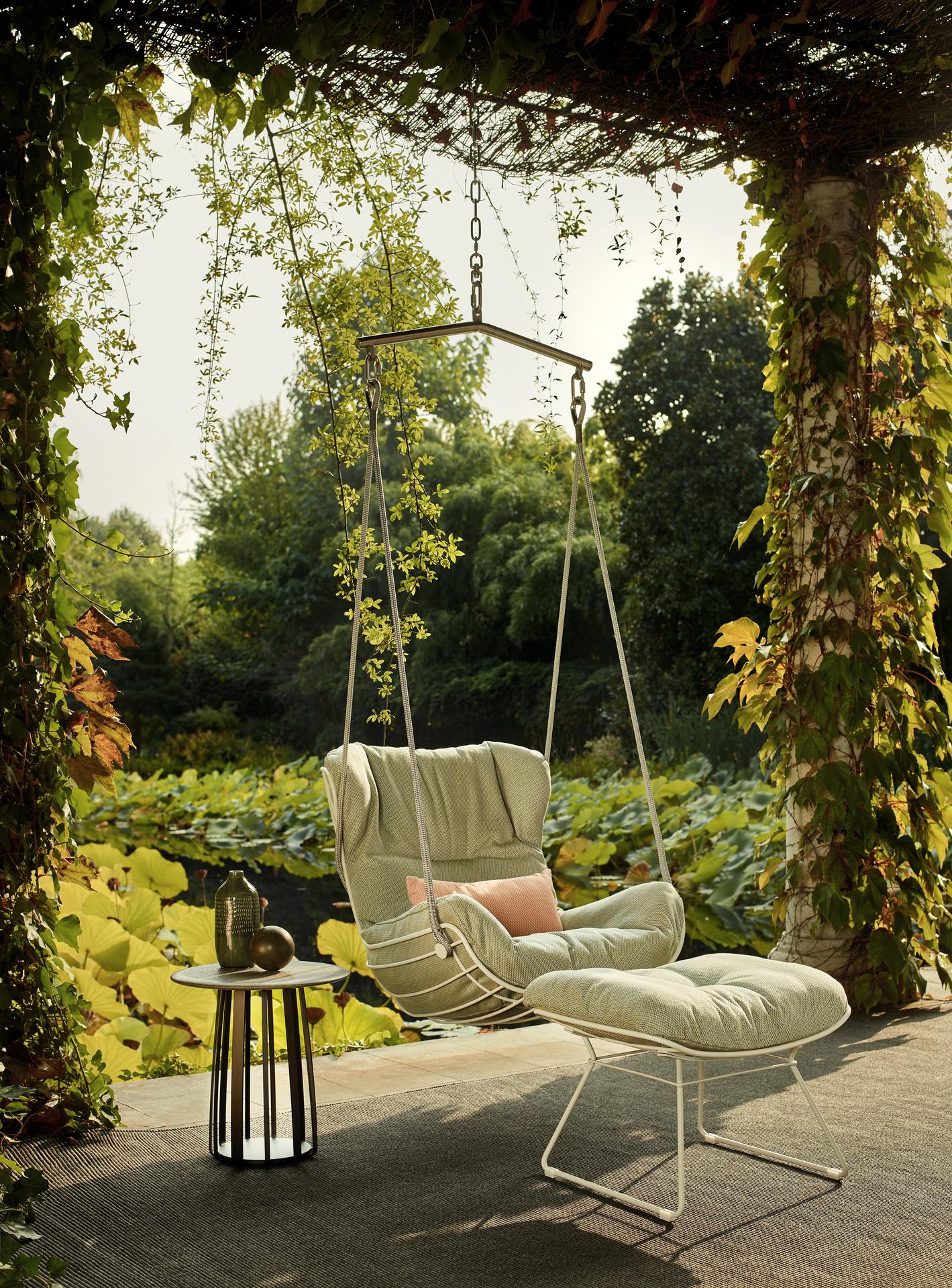 Freifrau Hängesessel unter Pergola mit Blick auf einen Teich und grüne Gartenlandschaft  