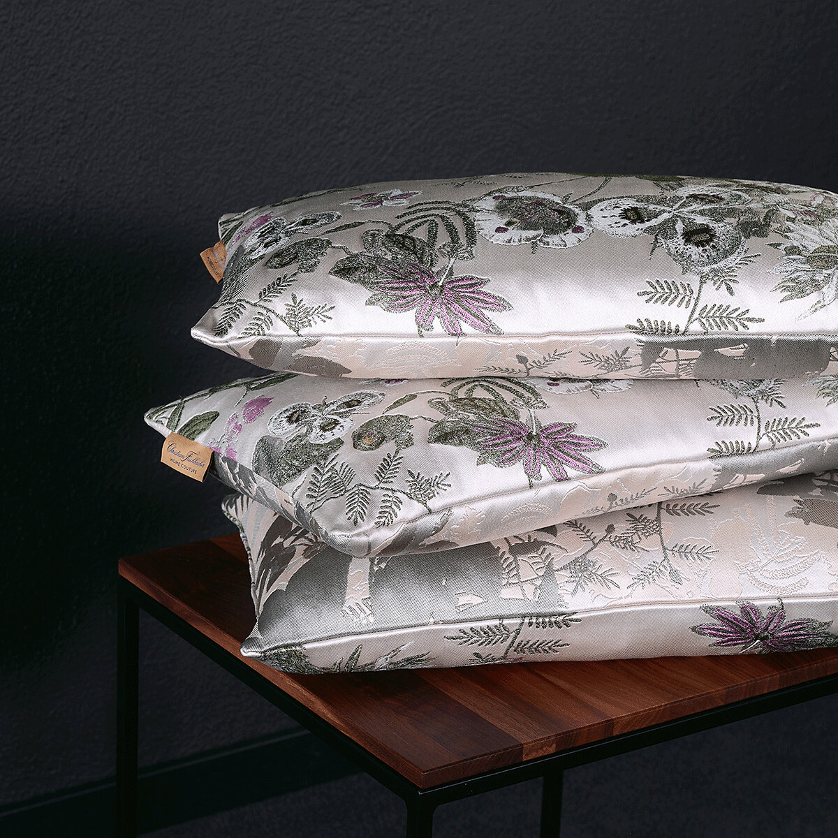 Drei Kissen mit glänzender Oberfläche und floralen Jacquard-Motiven