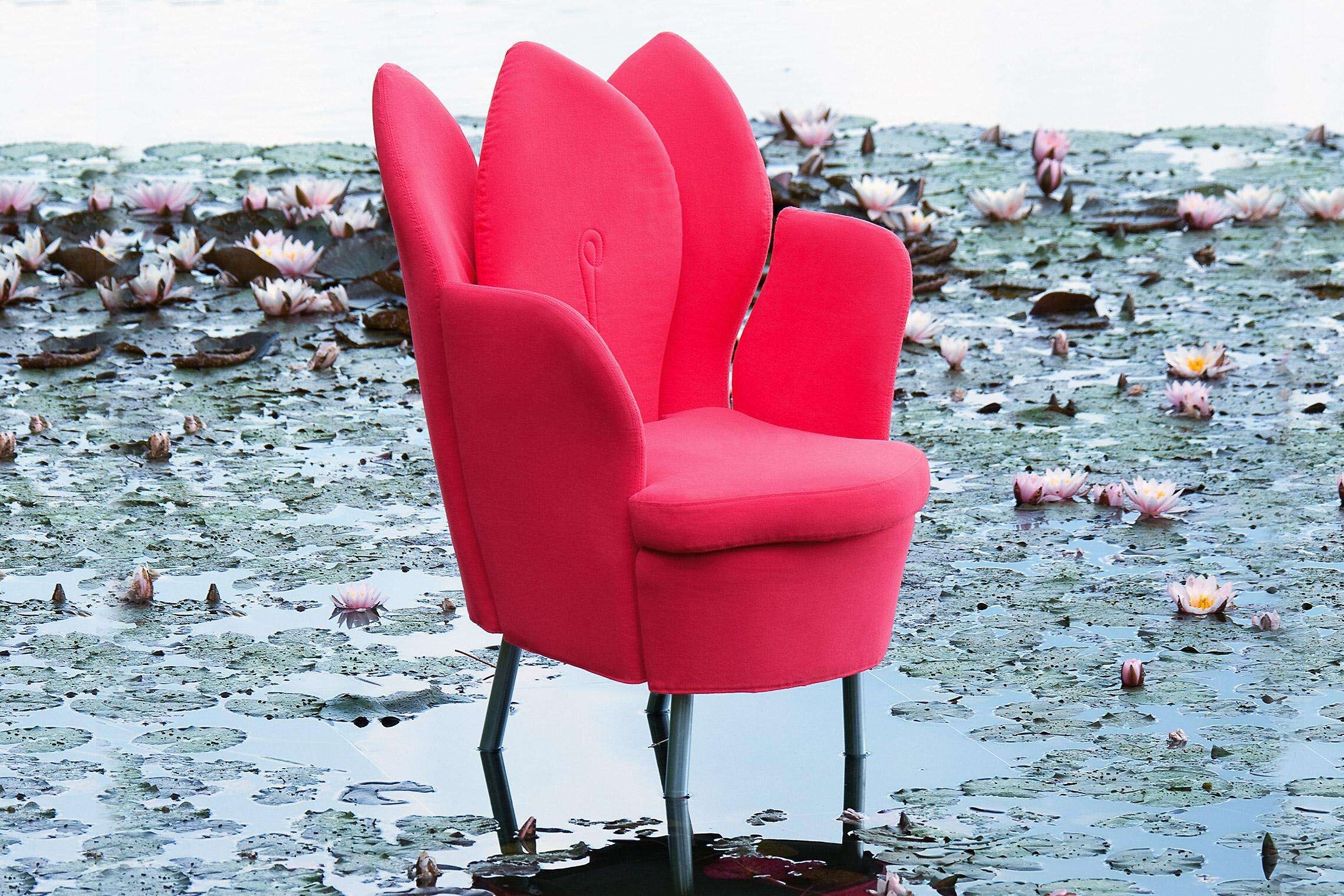Roter Polstersessel mit blütenartiger Rückenlehne, platziert im Seerosenteich  