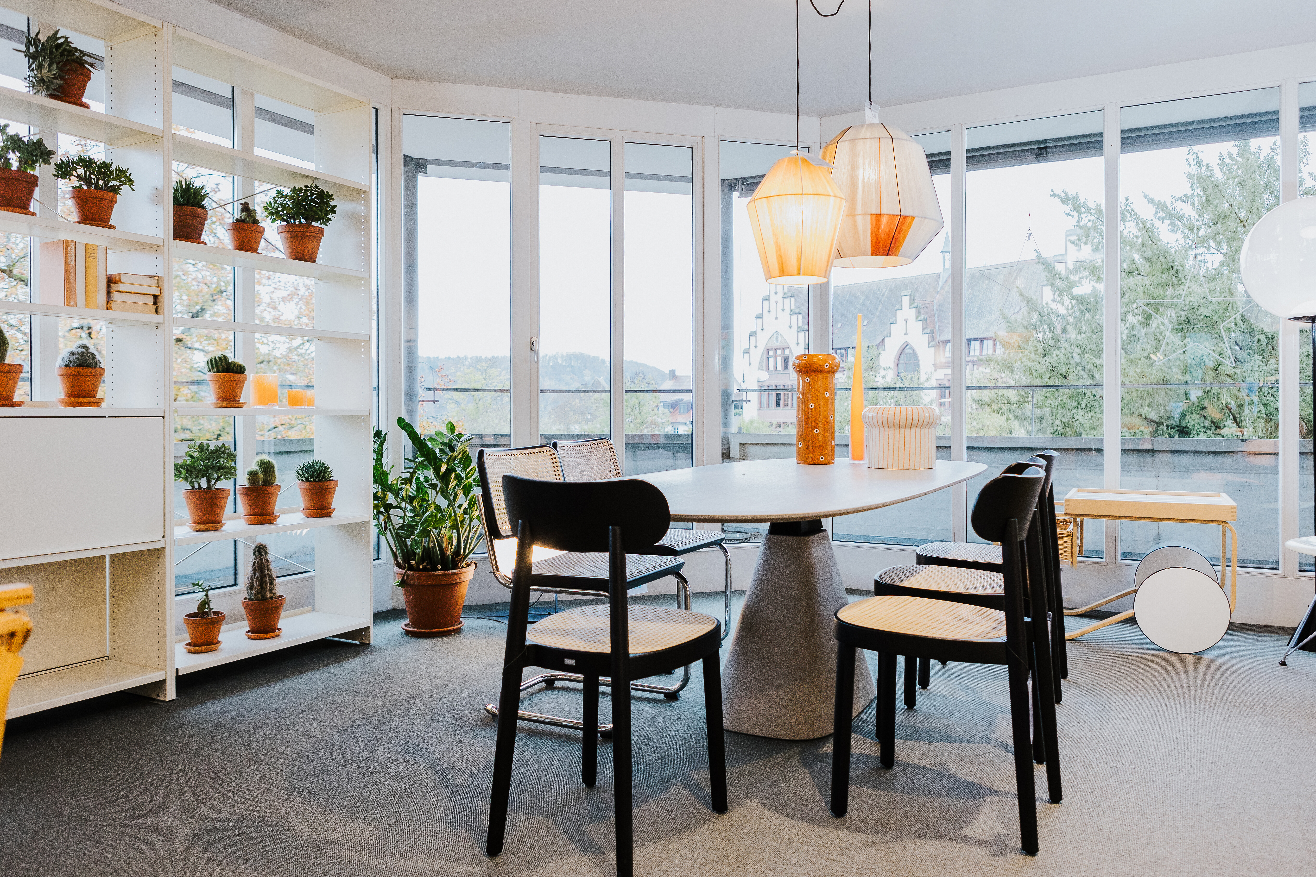 Essbereich mit schwarzen Stühlen von Thonet, runder Tisch und Leuchten vor Fensterfront