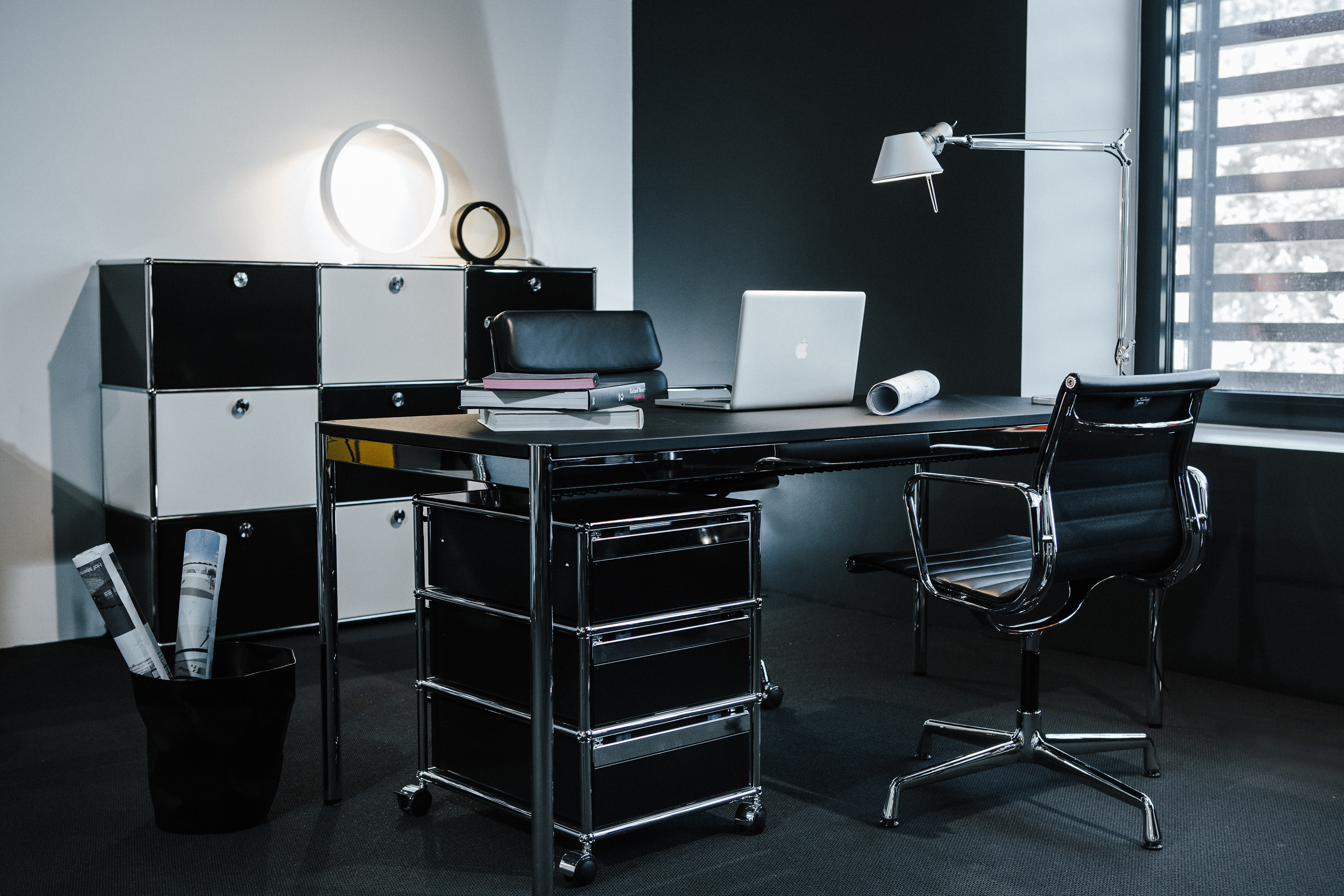 Büroszene mit schwarzem USM Haller Möbel, Aluminium Chair und Arbeitsfläche mit Laptop und Leuchte