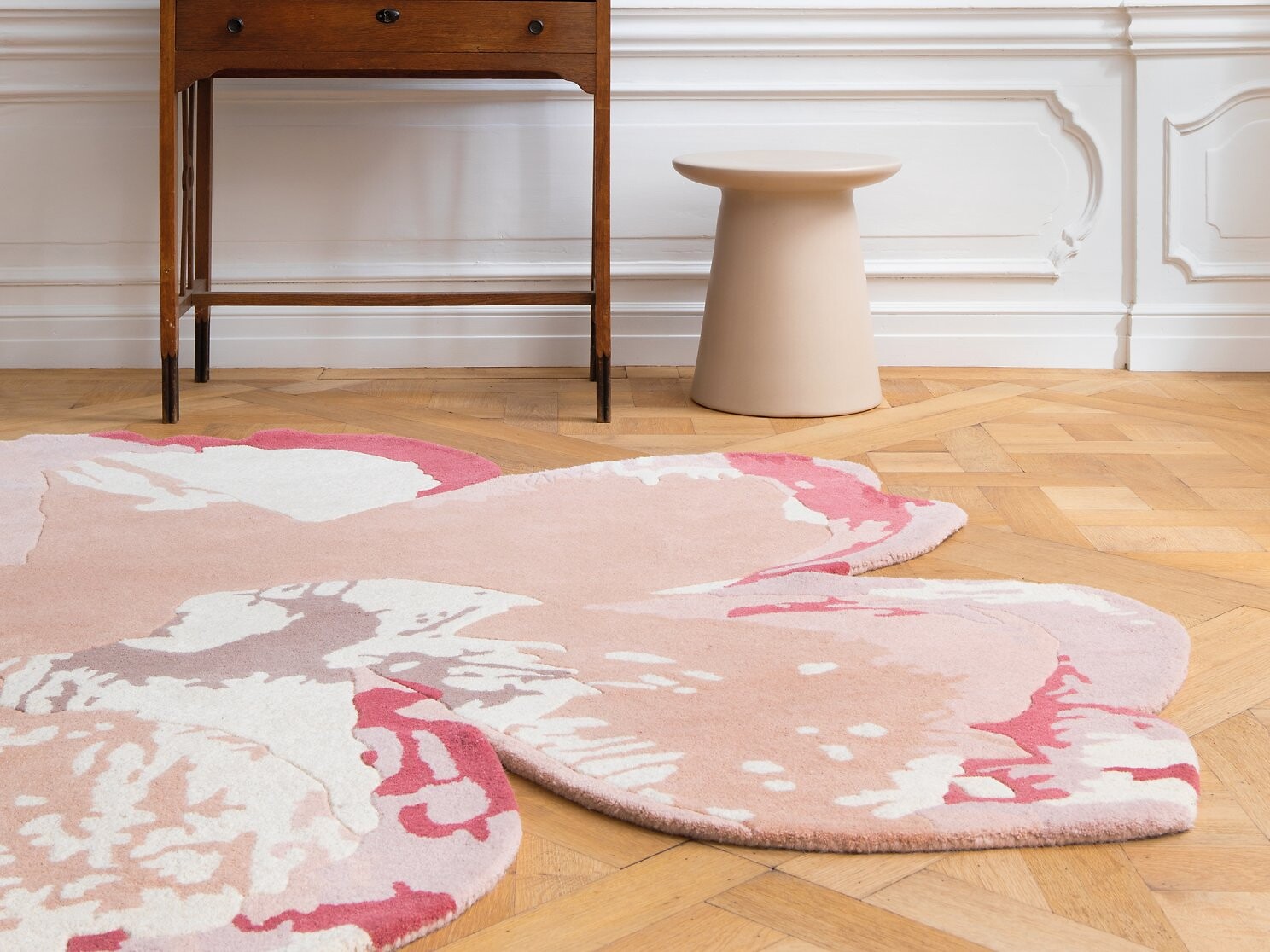 Rosa Teppich mit großflächigem Blütenmotiv auf Fischgrätparkett  