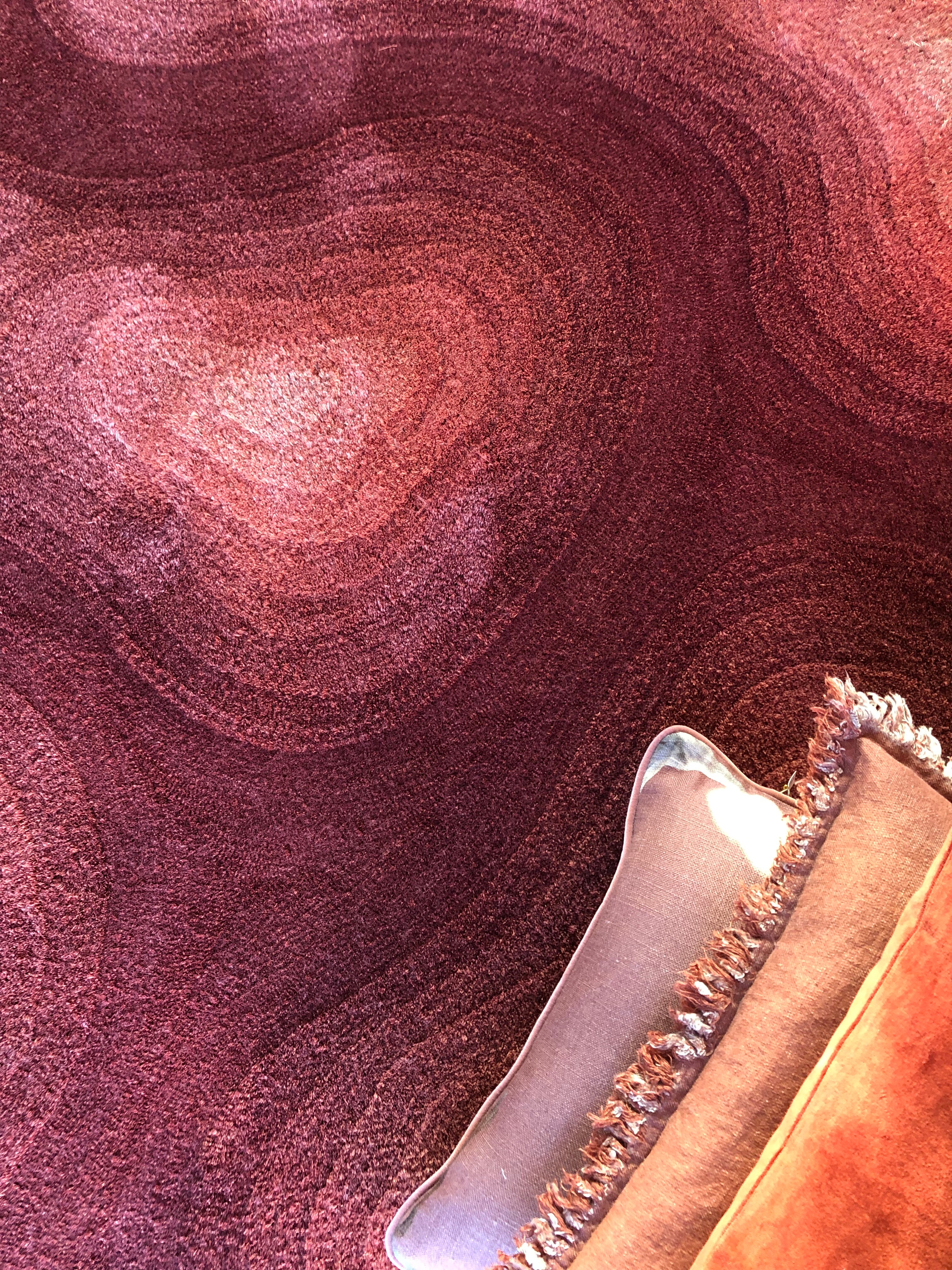 Nahaufnahme eines Teppichs mit konzentrischen Farbverläufen in Rosé- und Rottönen