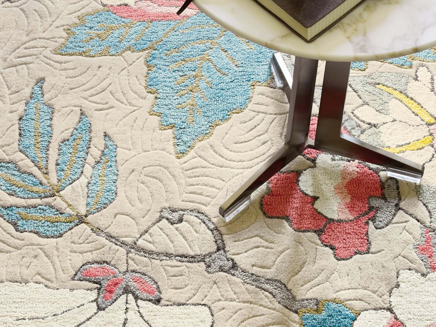 Detailaufnahme eines floralen Teppichs in Beige, Blau und Rot unter Tisch  