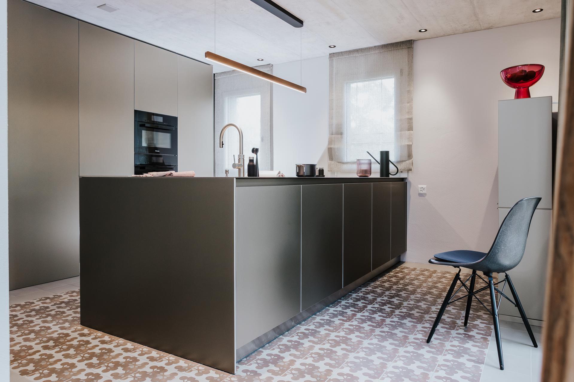 Küche mit griffloser Insel, matten Fronten und gemustertem Bodenbelag in wohnlich-modernem Ambiente