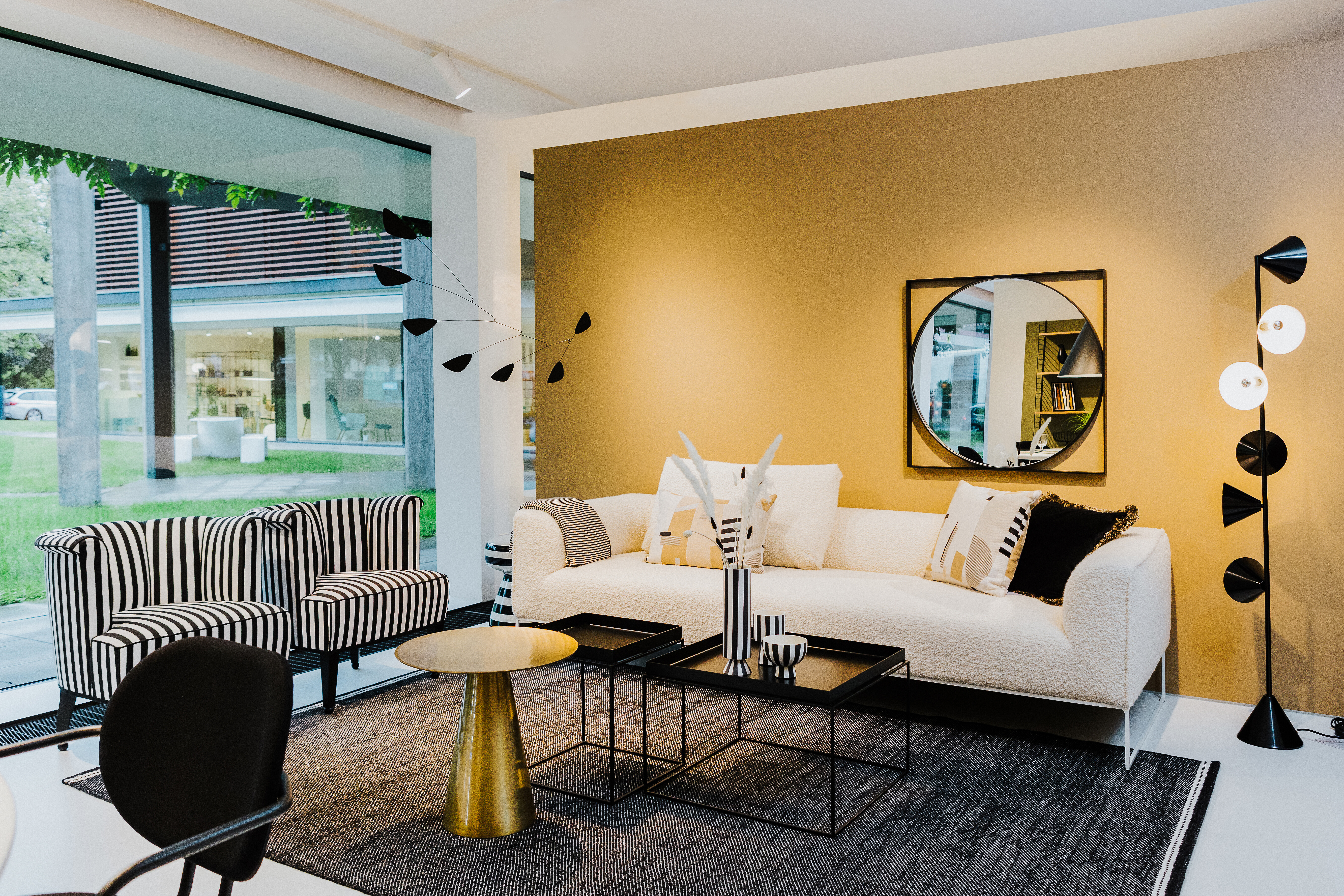 Wohnbereich im Schaufenster Tiengen mit goldener Wand, grafischen Leuchten und Streifenmöbeln