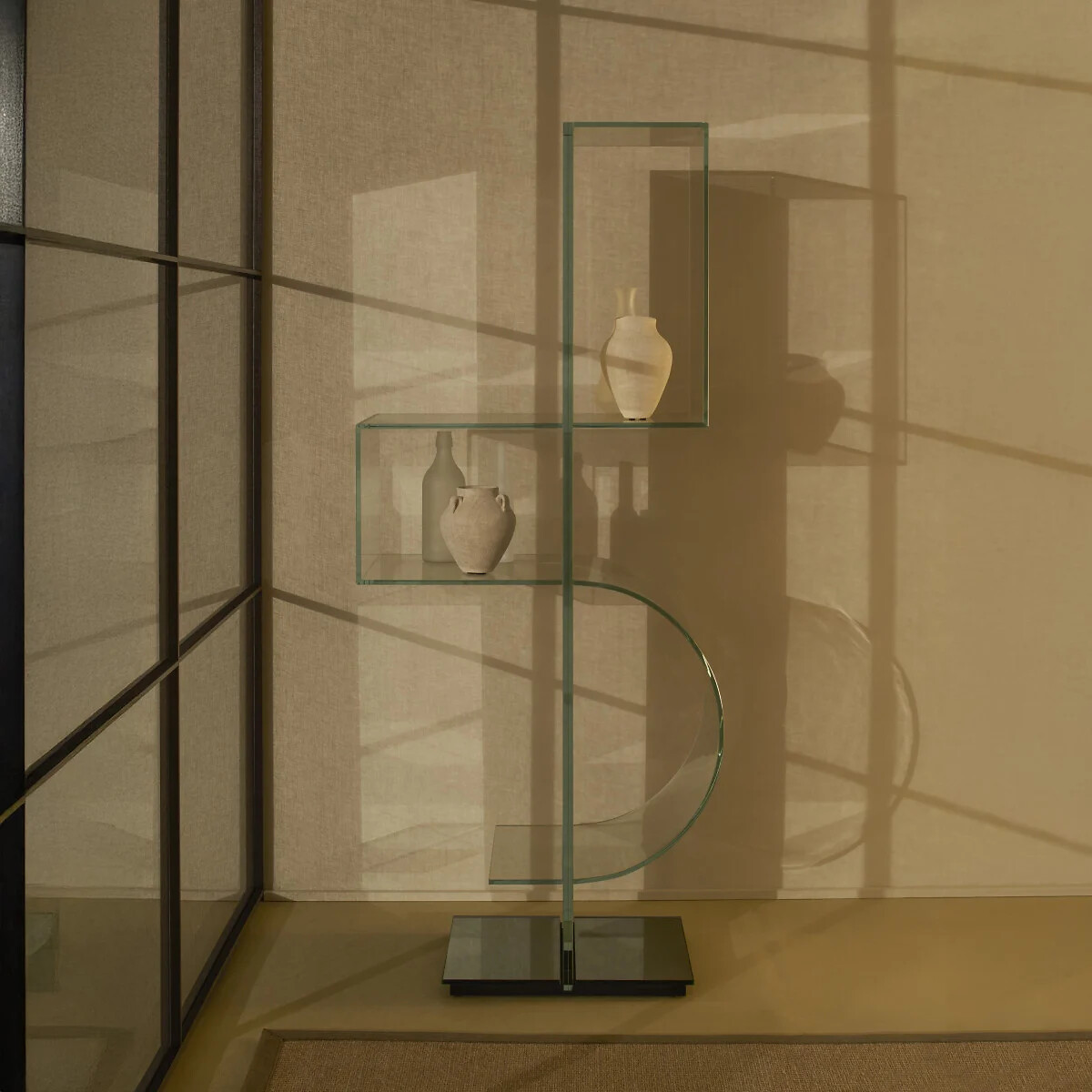 Regal aus Glas mit asymmetrischer Formgebung in beleuchtetem Raum mit Schattenwurf.
