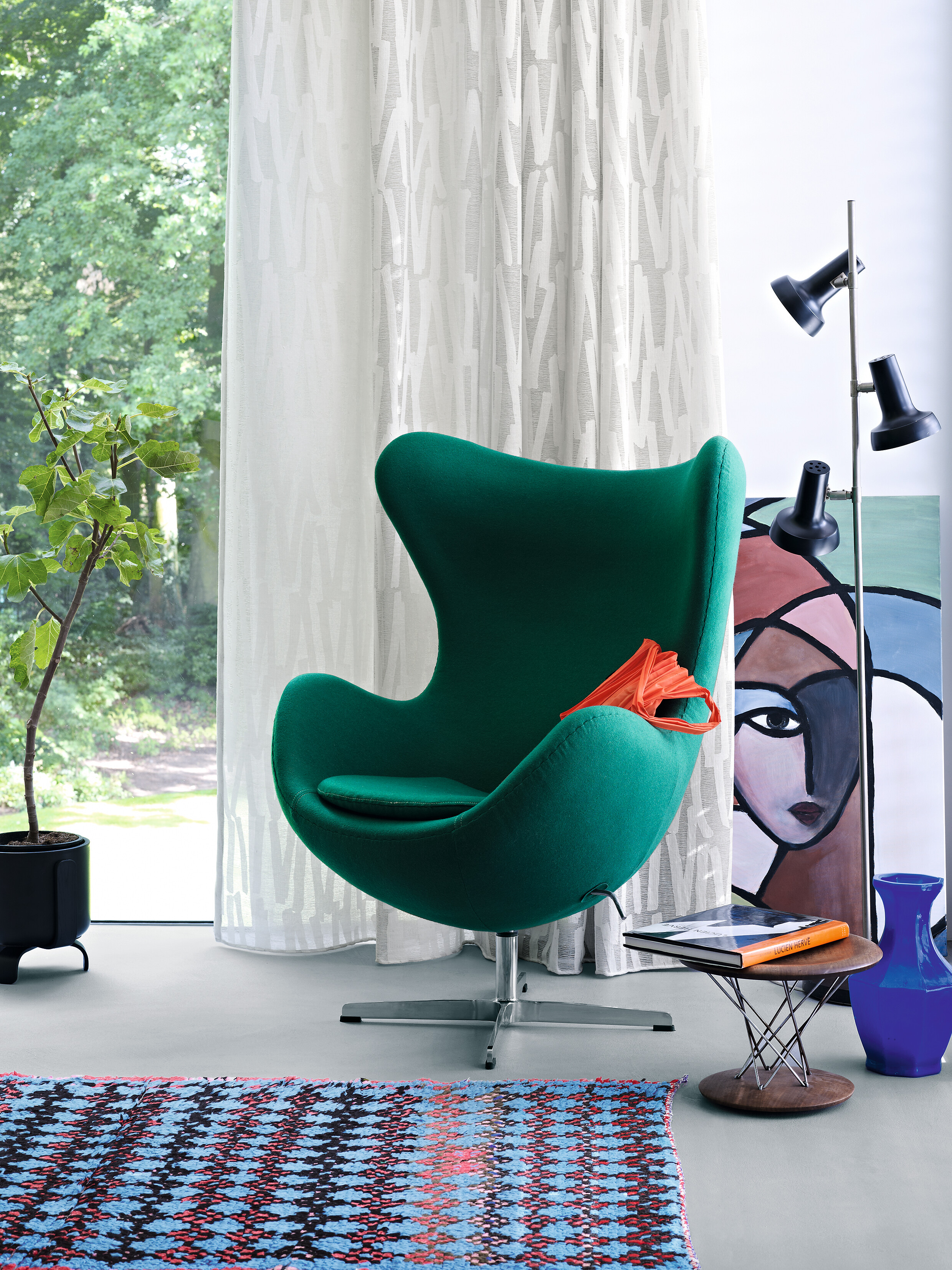 Grüner Sessel vor lichtem Vorhang mit grafischer Webstruktur