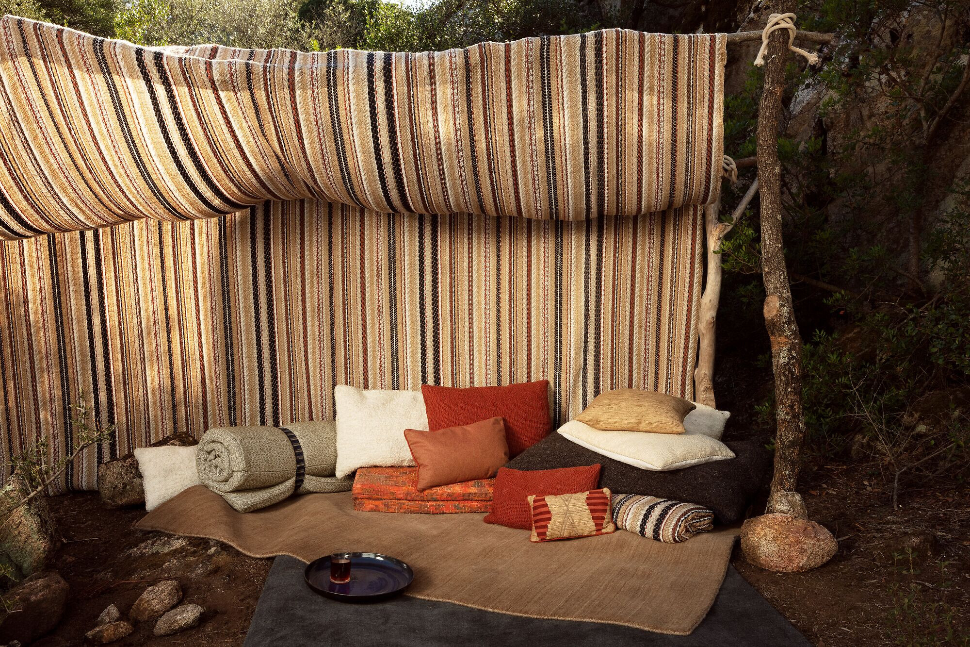 Outdoorbereich mit gestreiften Textilien, Kissen und geerdeten Farbtönen  