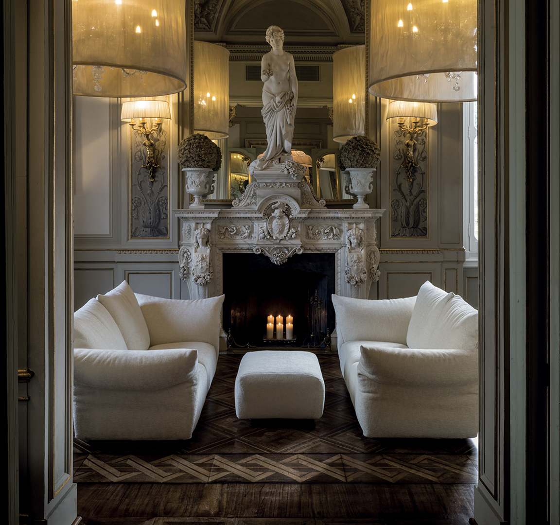 Zwei weiße Sofas Standard mit Hocker vor Kamin und Skulptur in klassischem Interieur mit Holzparkett