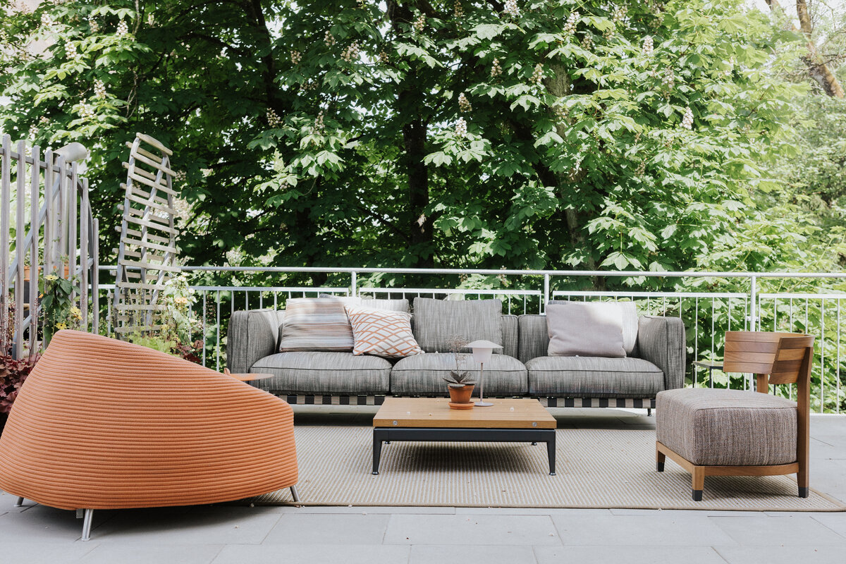 Moderne Outdoor-Sitzgruppe mit markantem orangefarbenem Sessel auf der Terrasse von Seipp Wohnen Waldshut