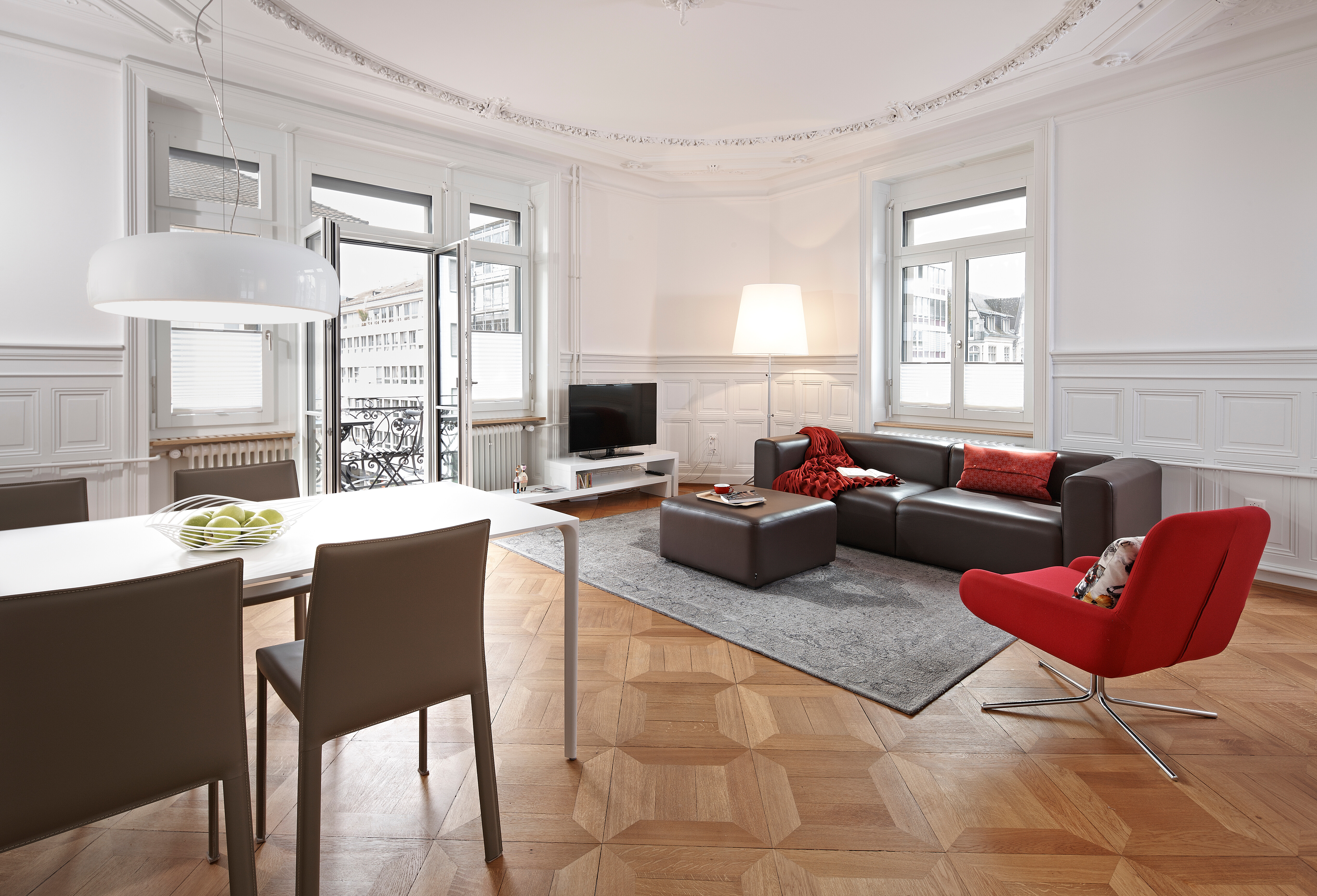 Wohnraum mit Parkett, Designmöbeln und Stuckdecke in einer Künstlerwohnung beim Zürcher Opernhaus