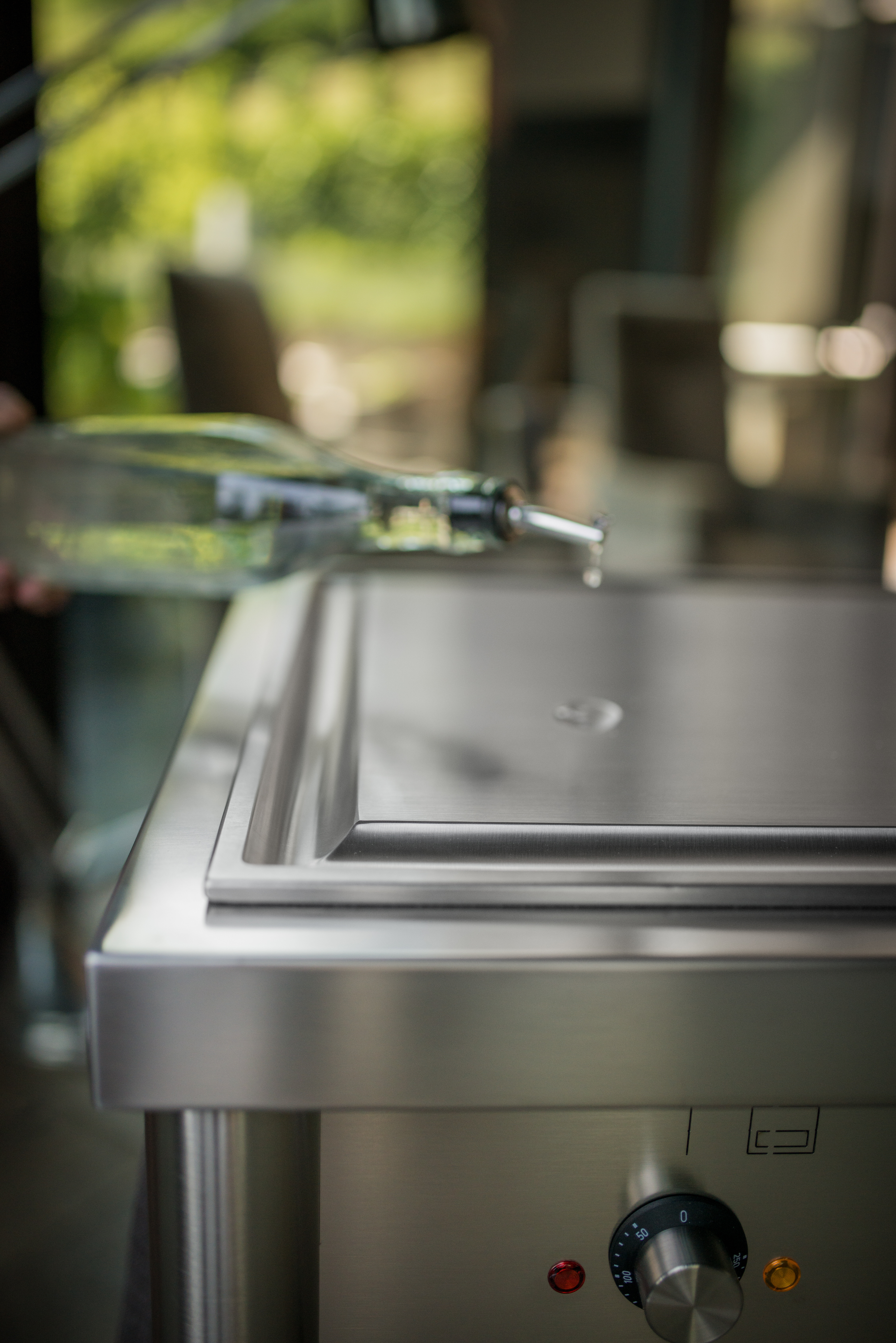 Detailansicht einer Edelstahlfläche mit eingelassener Platte und Drehregler