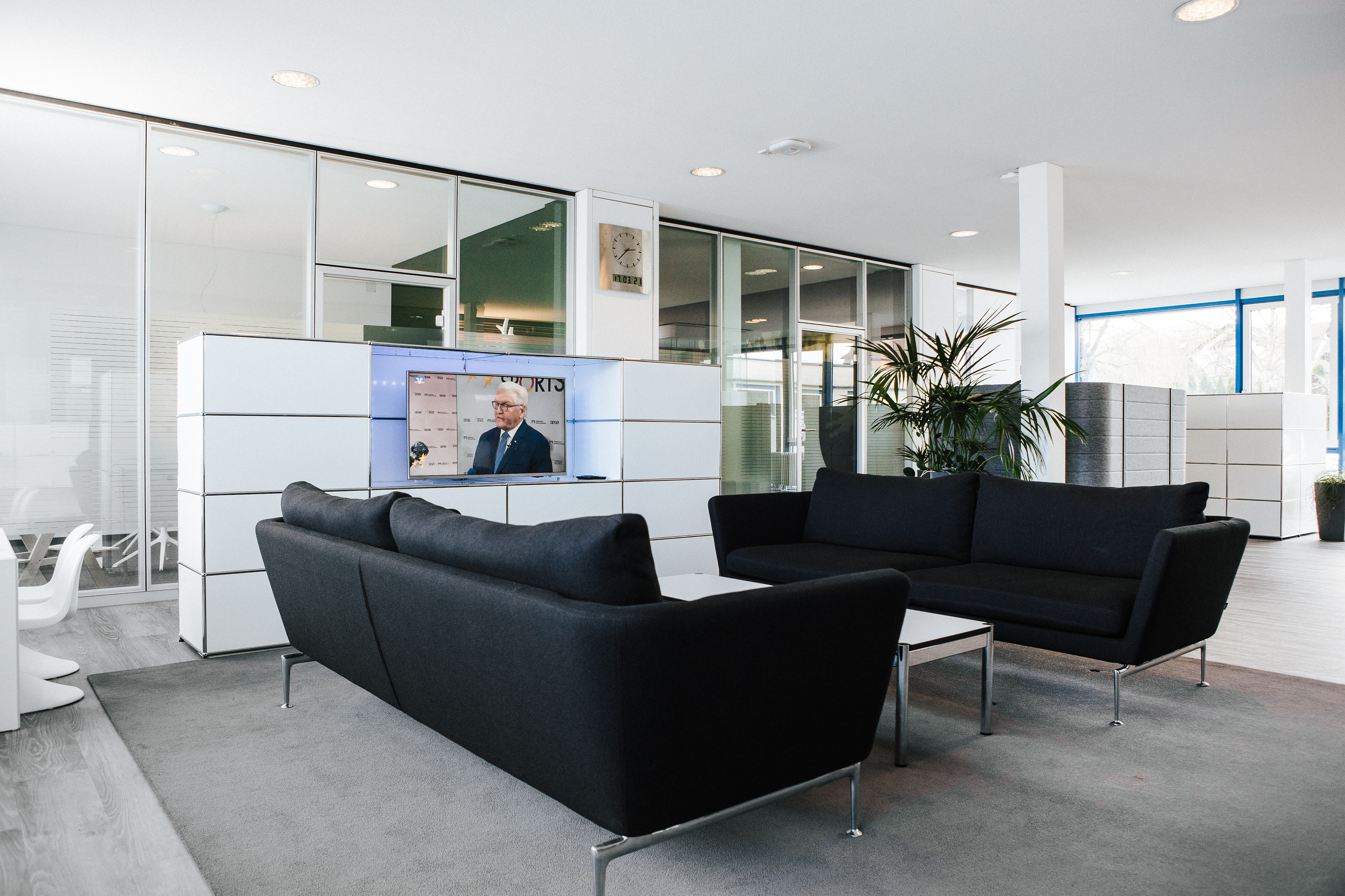 Kundenlounge der Volksbank Erzingen mit zwei schwarzen Sofas, Couchtisch und Medienelement