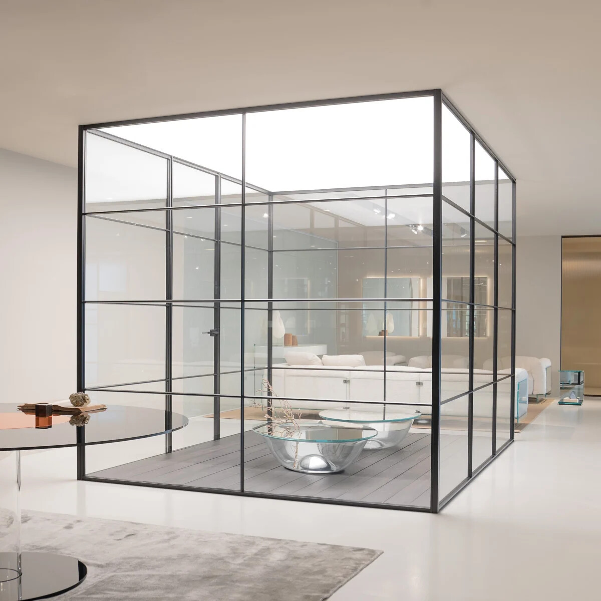 Glaskubus mit schwarzer Rasterstruktur als transparenter Raum im offenen Wohnbereich.