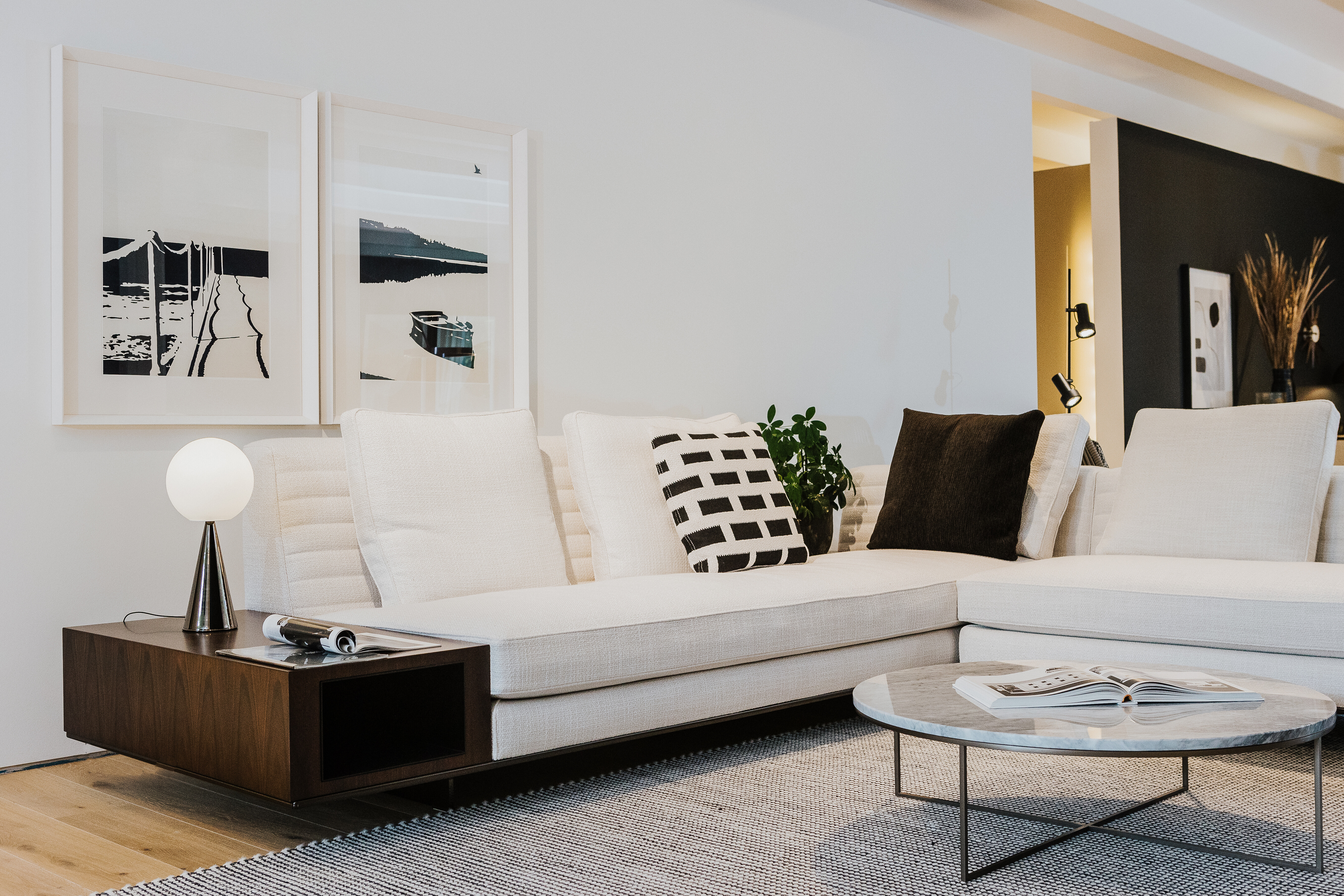 Moderne Wohnszene mit Ecksofa in Naturtönen, Couchtisch mit Marmorplatte und gerahmten Fotografien