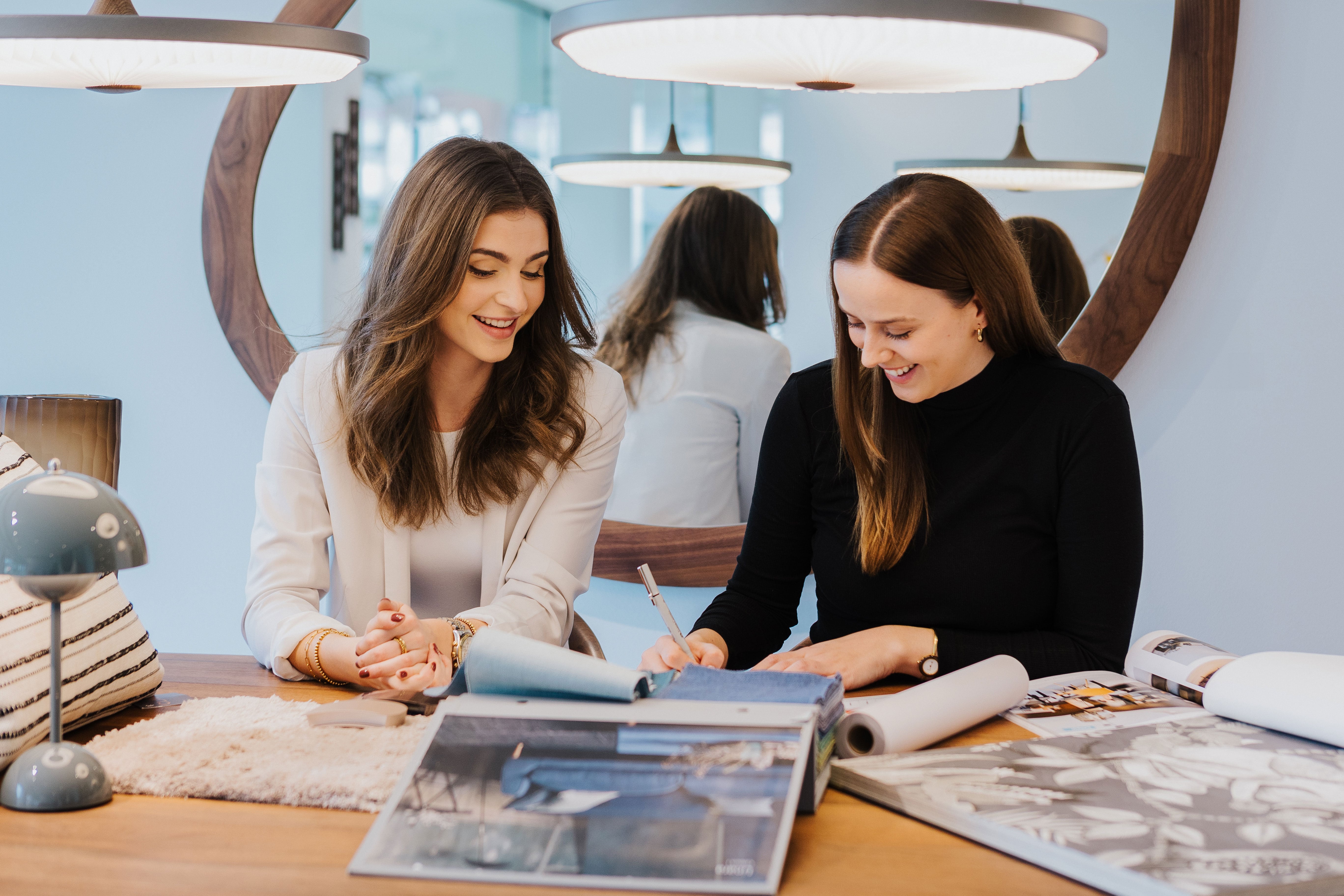 Zwei Mitarbeiterinnen von Seipp Wohnen im Planungsgespräch mit Stoffmustern und Plänen im Showroom.