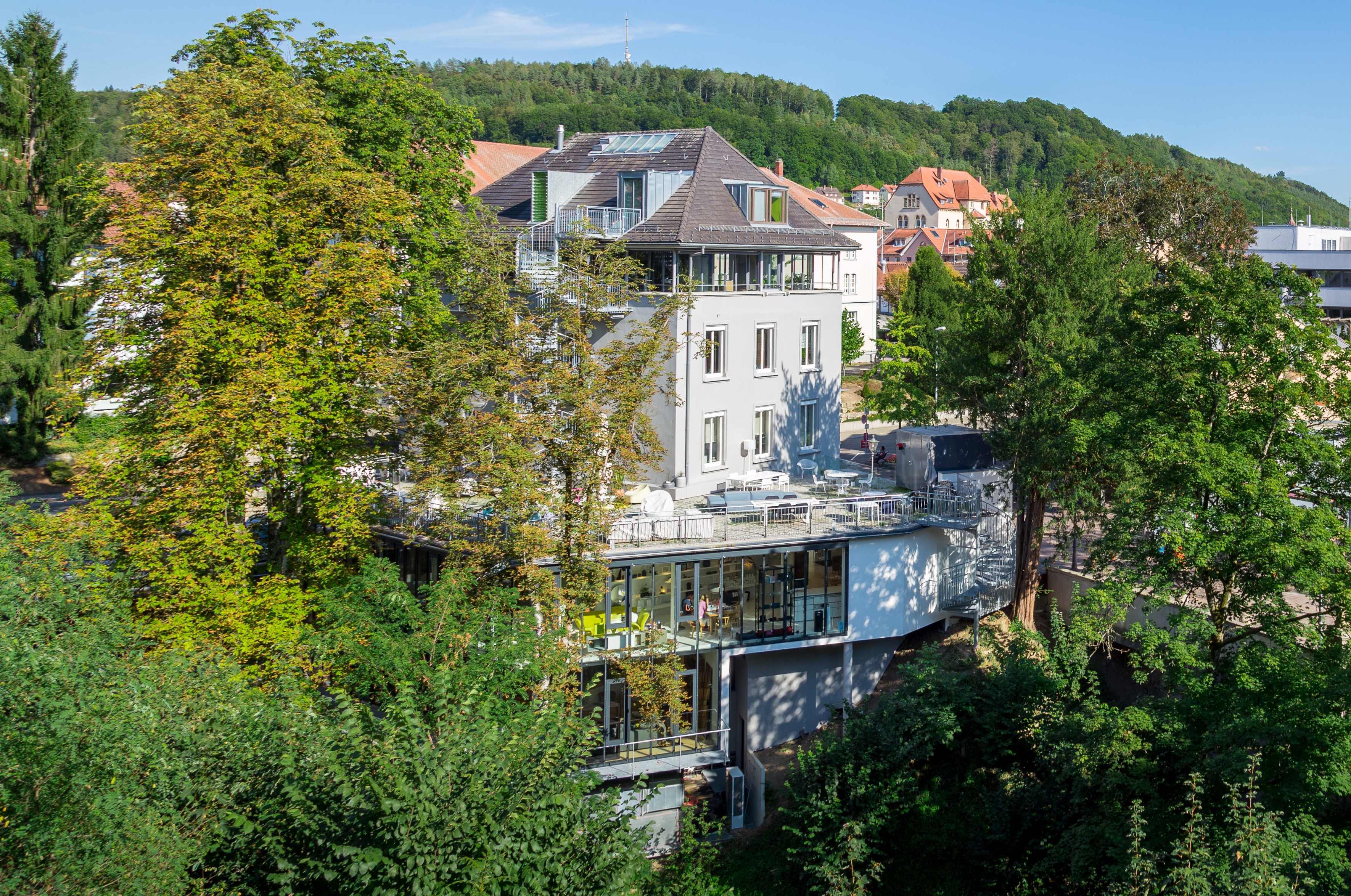 Blick auf das Einrichtungshaus Seipp Wohnen in Waldshut, umgeben von Bäumen, mit sichtbarer Terrasse und moderner Fassade.