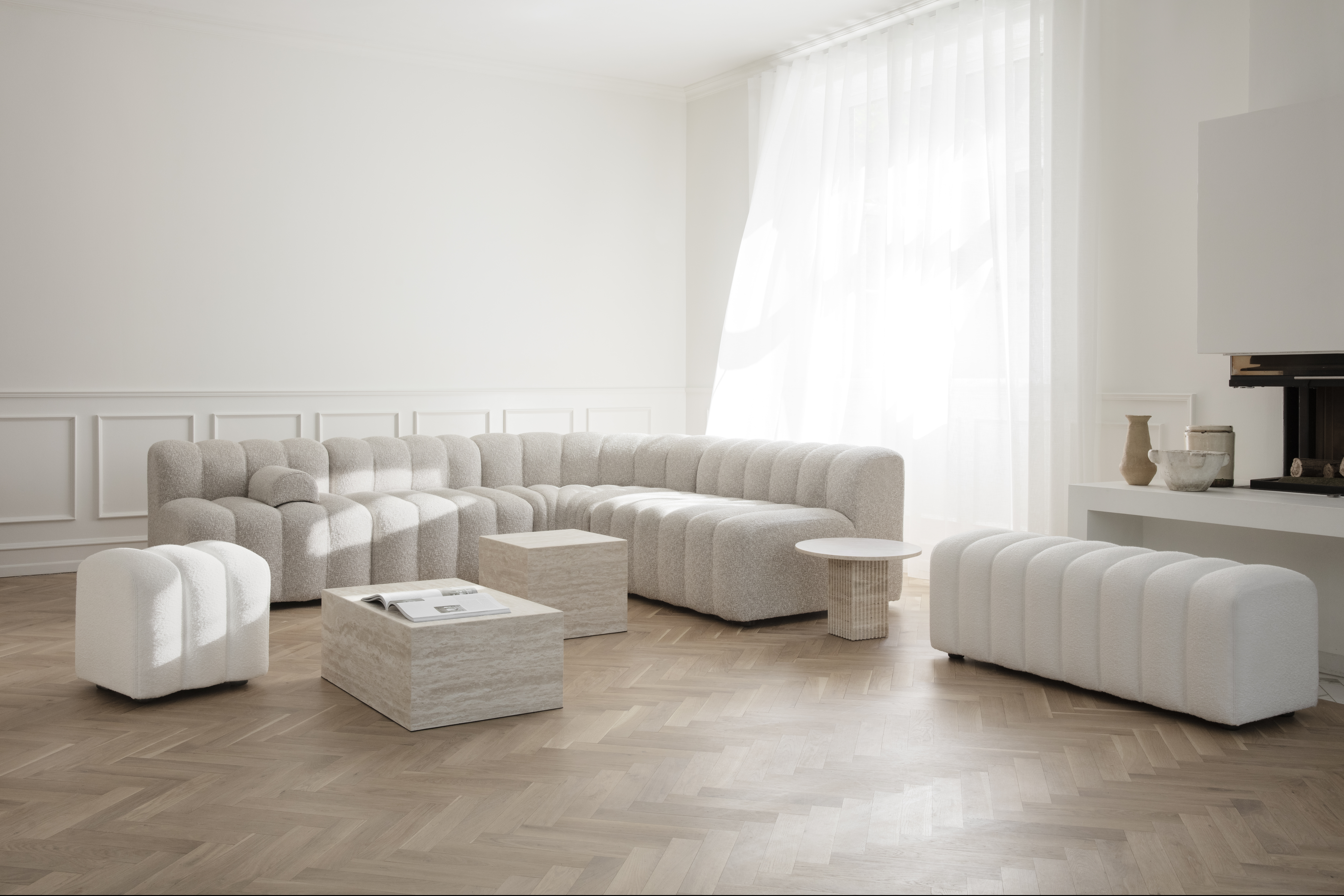 Modulares, beigefarbenes Sofa in L-Form mit Hocker und Couchtisch in hellem Raum  
