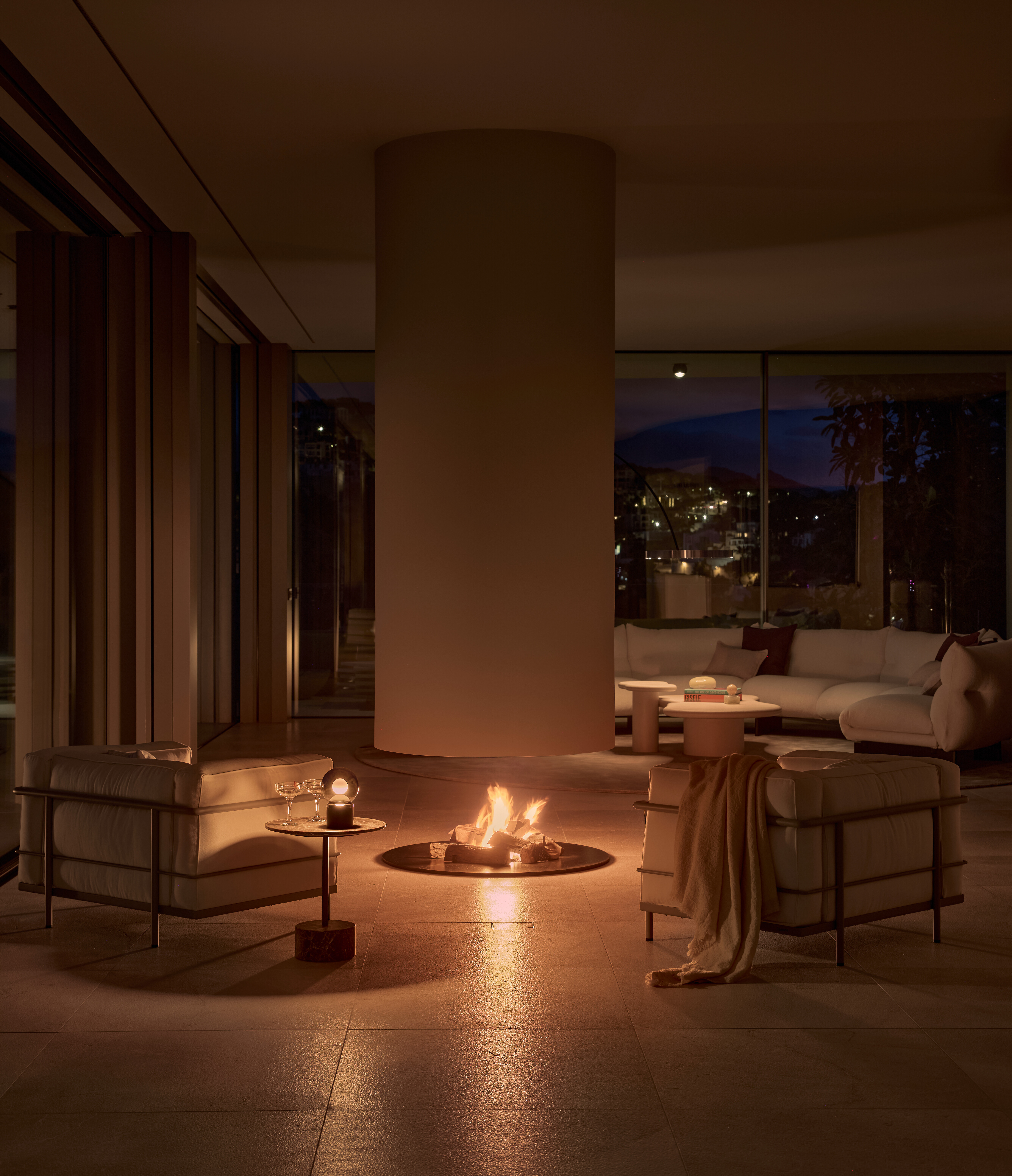 Luna pura von Occhio auf Beistelltisch neben Sesseln vor offener Feuerstelle