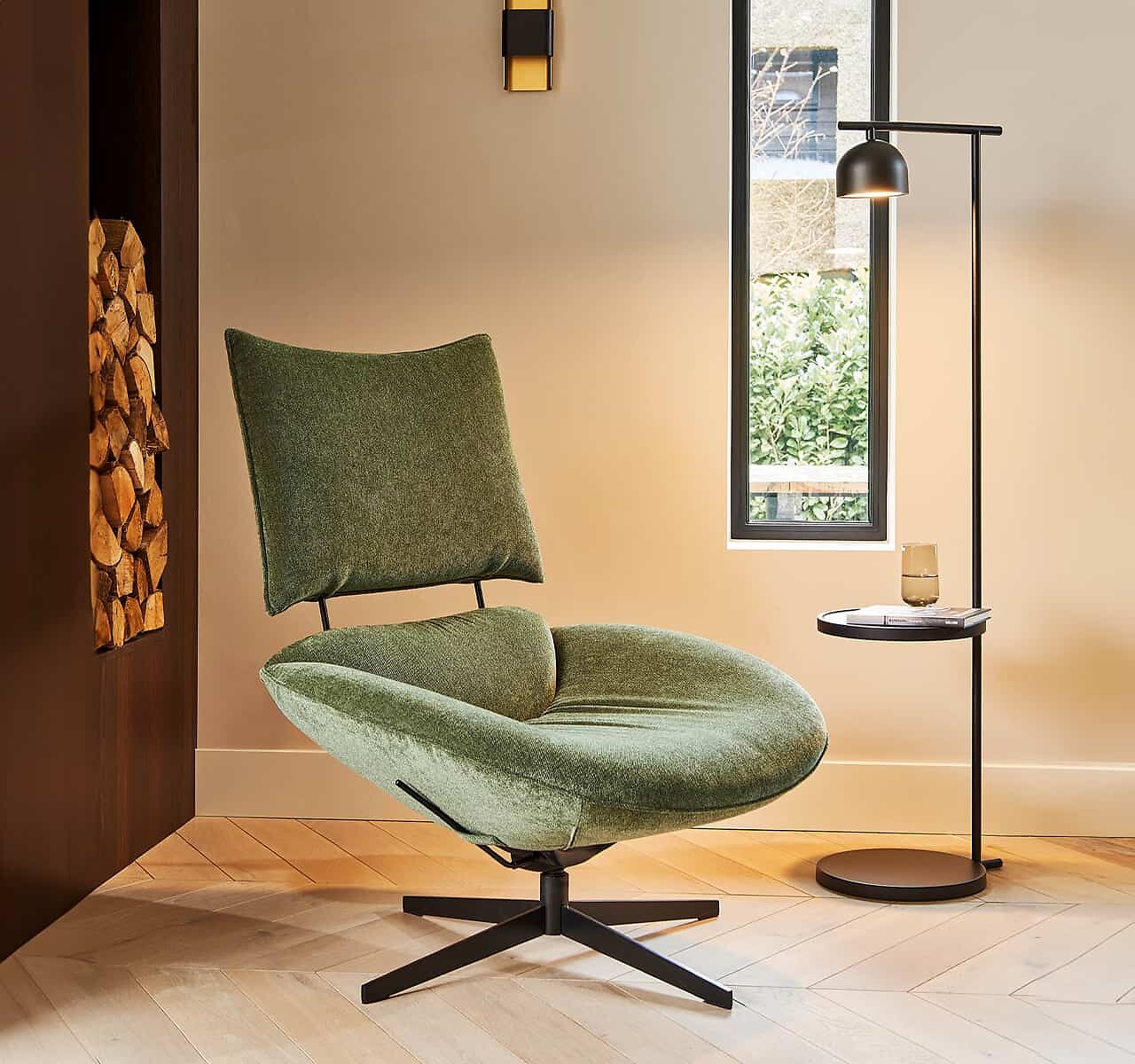 Grüner Drehsessel mit hoher Rückenlehne auf Holzfußboden neben Beistelltisch