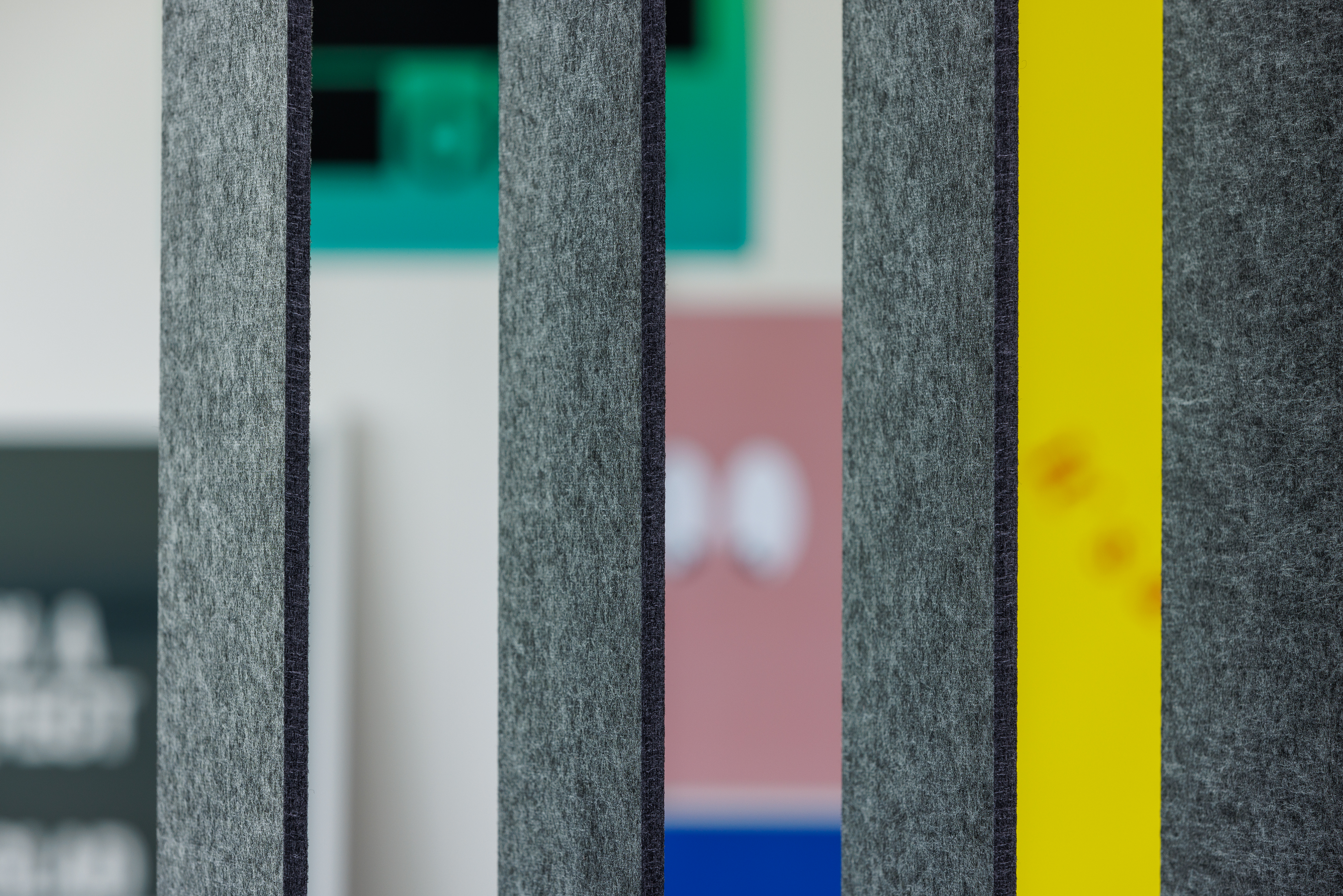 Vertikale textile Lamellen in Grau mit Akzenten in Gelb vor unscharfem Hintergrund im Raum  