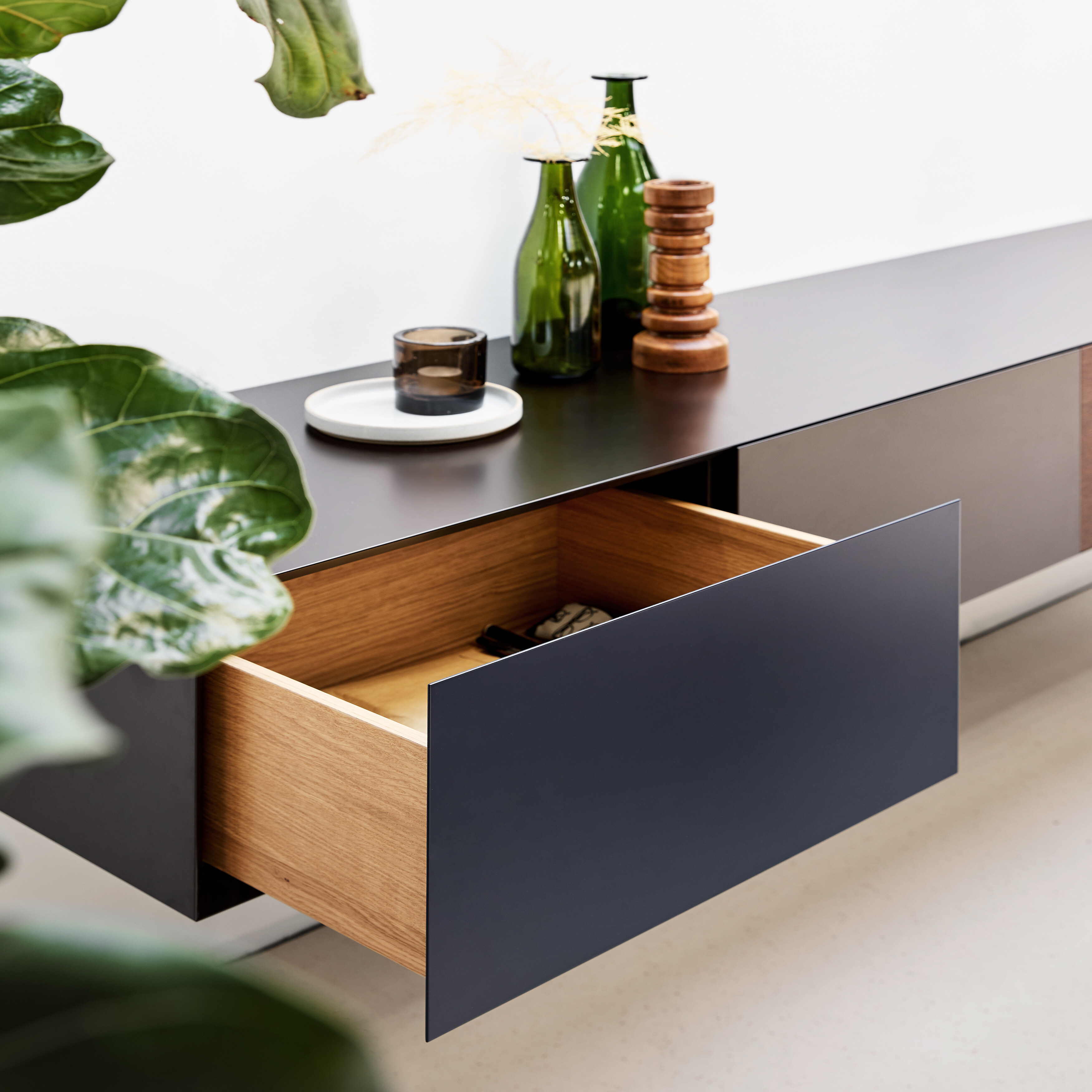 Sideboard mit geöffneter Schublade aus schwarzer Front und naturbelassenem Innenkorpus