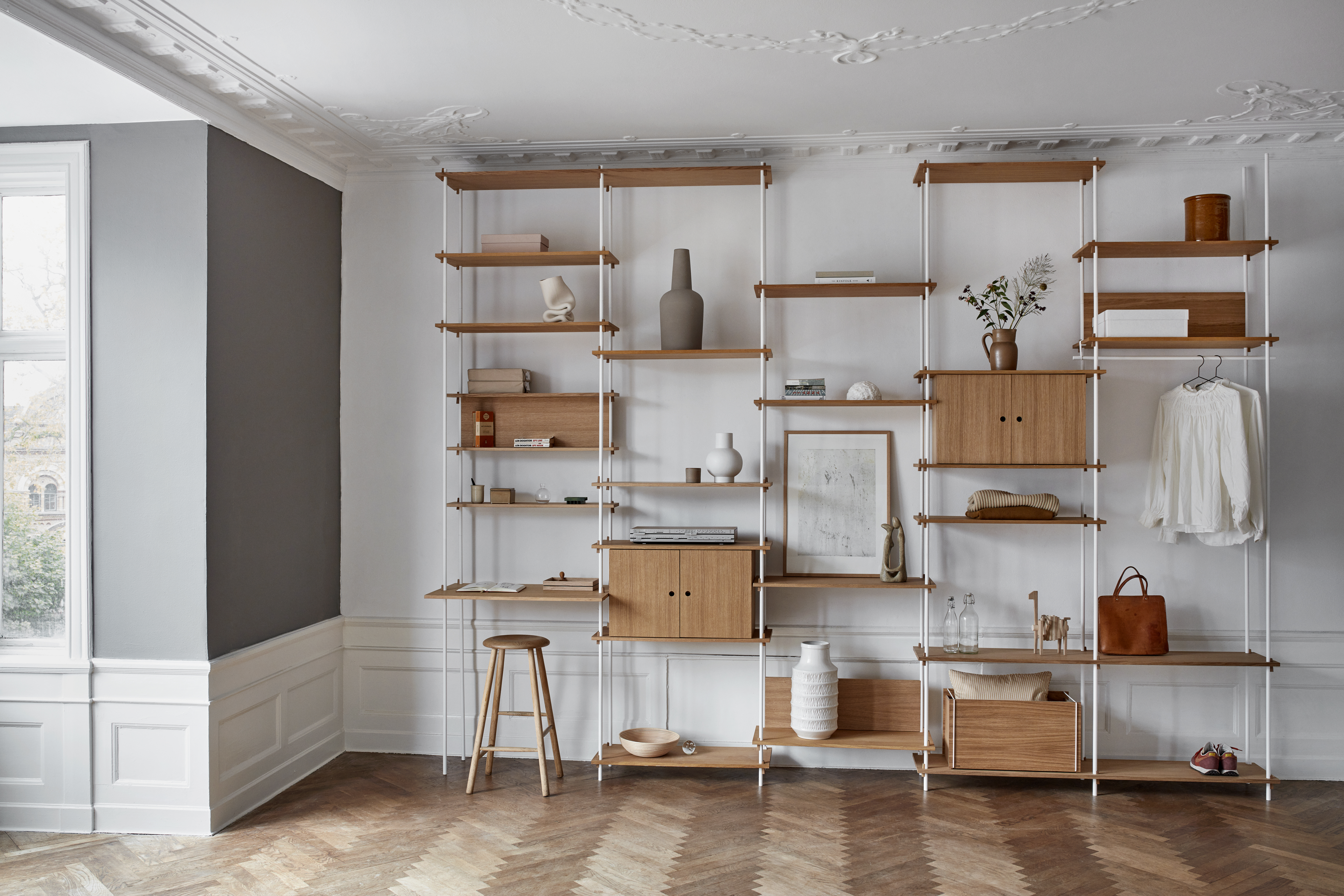 Wandregalsystem mit Holzablagen und weißen Trägern, teilweise mit Türen und Schubladen  