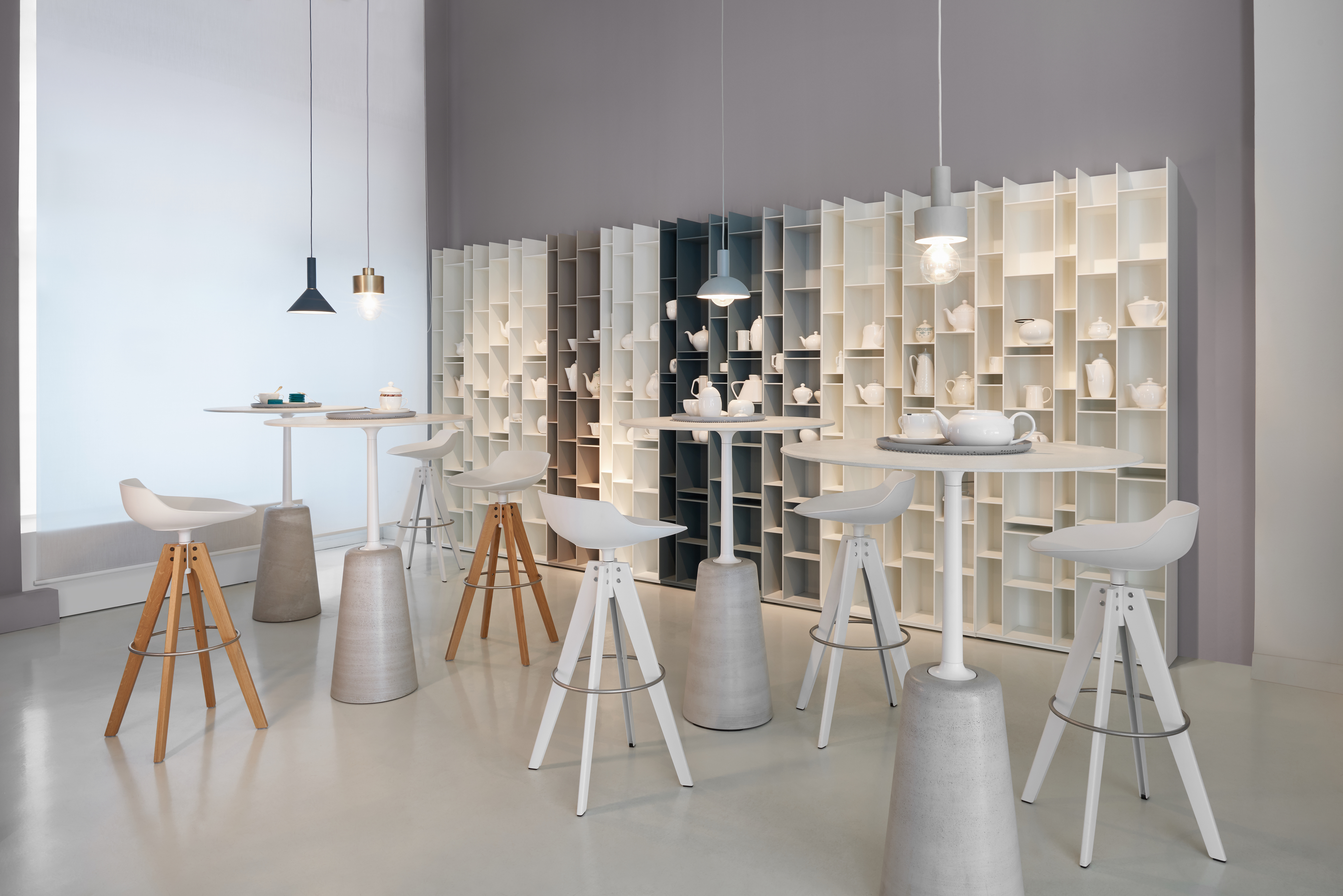 Weiße MDF Italia Barhocker an hohen Tischen vor modularen Regalen mit Leuchten